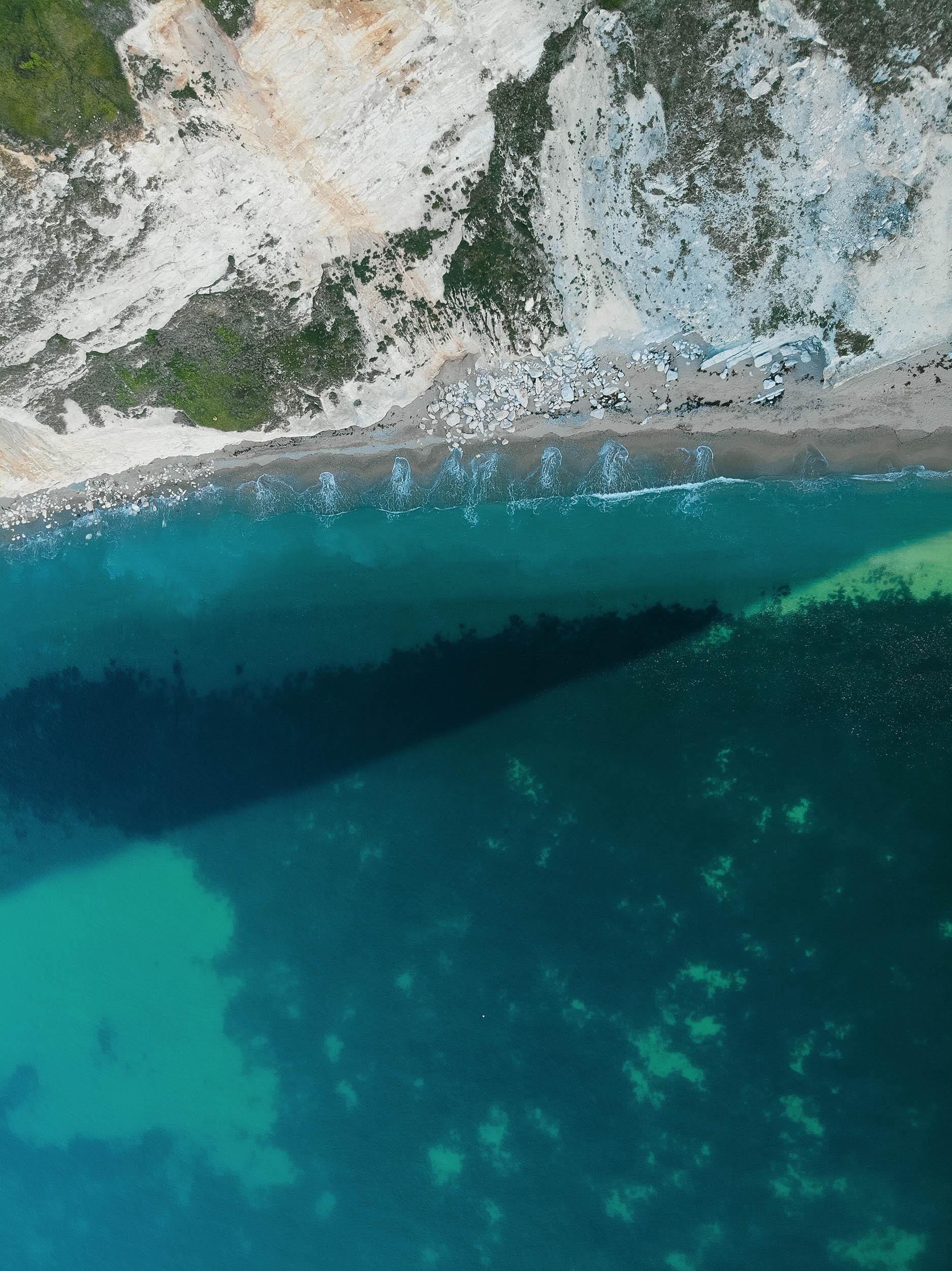 Aerial view of the cliff top with sea water lapping at the shore