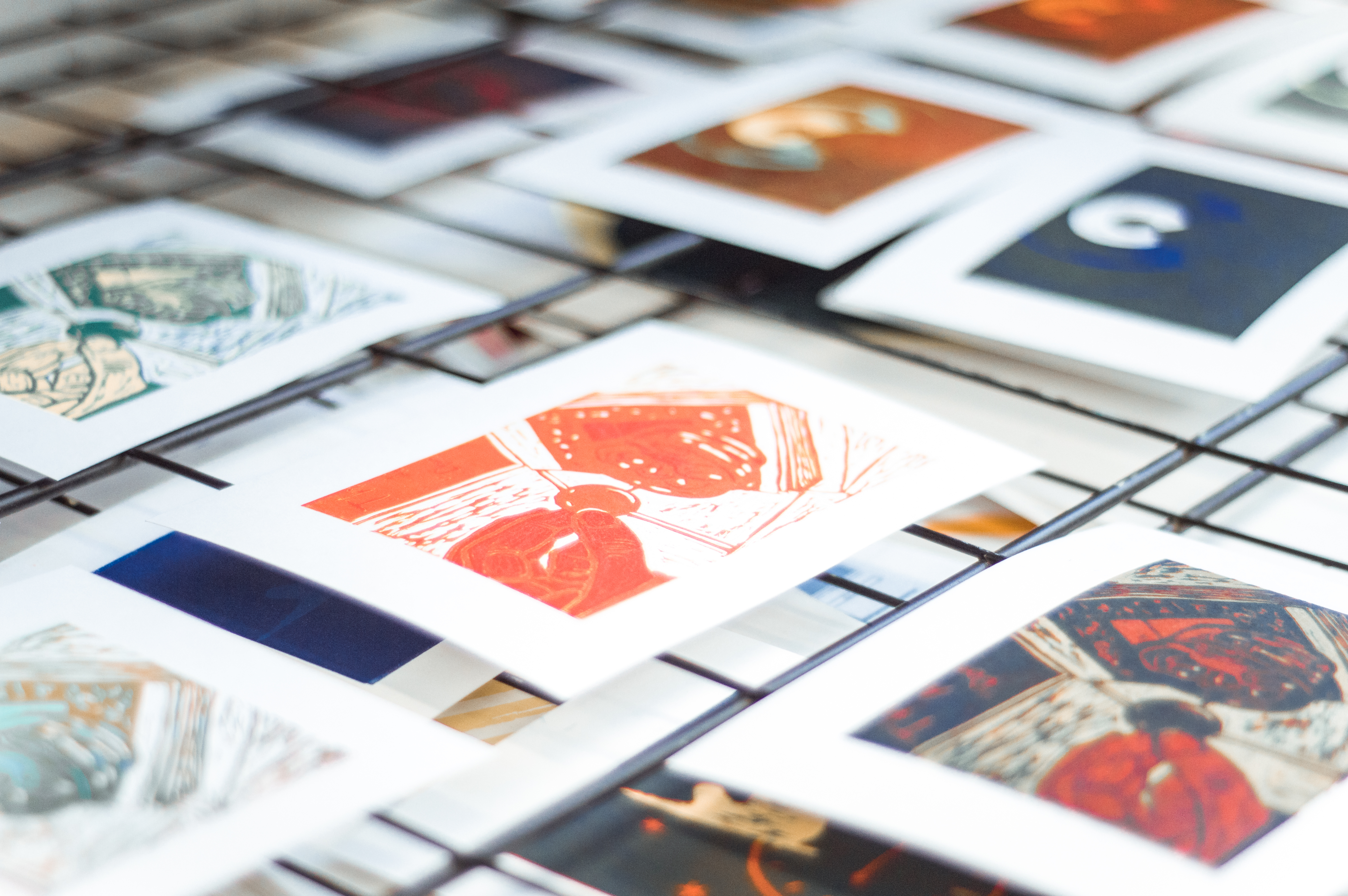 A collection of printed artworks drying on racks.