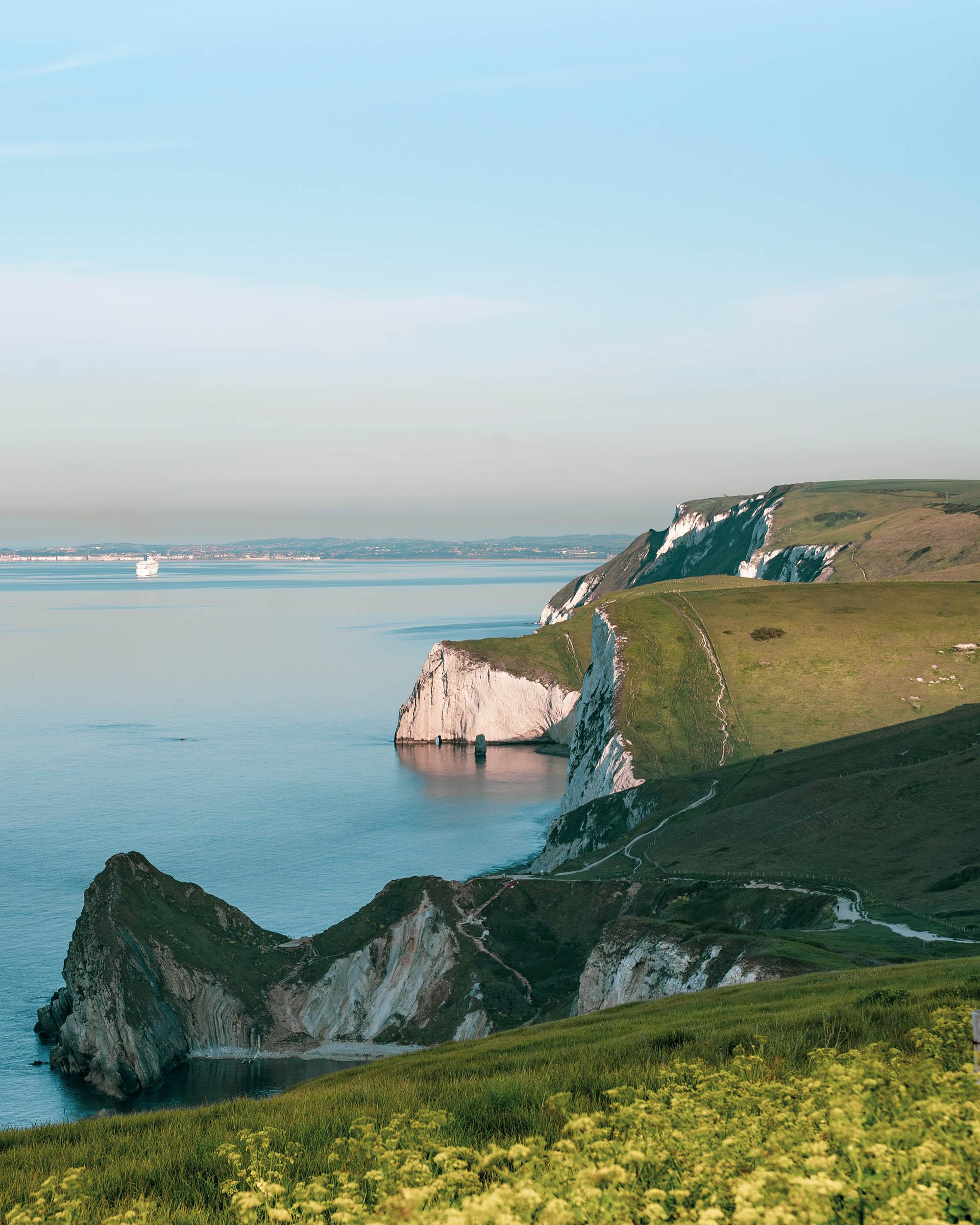 View of a coastline with rocks and cliffsides in the foreground.