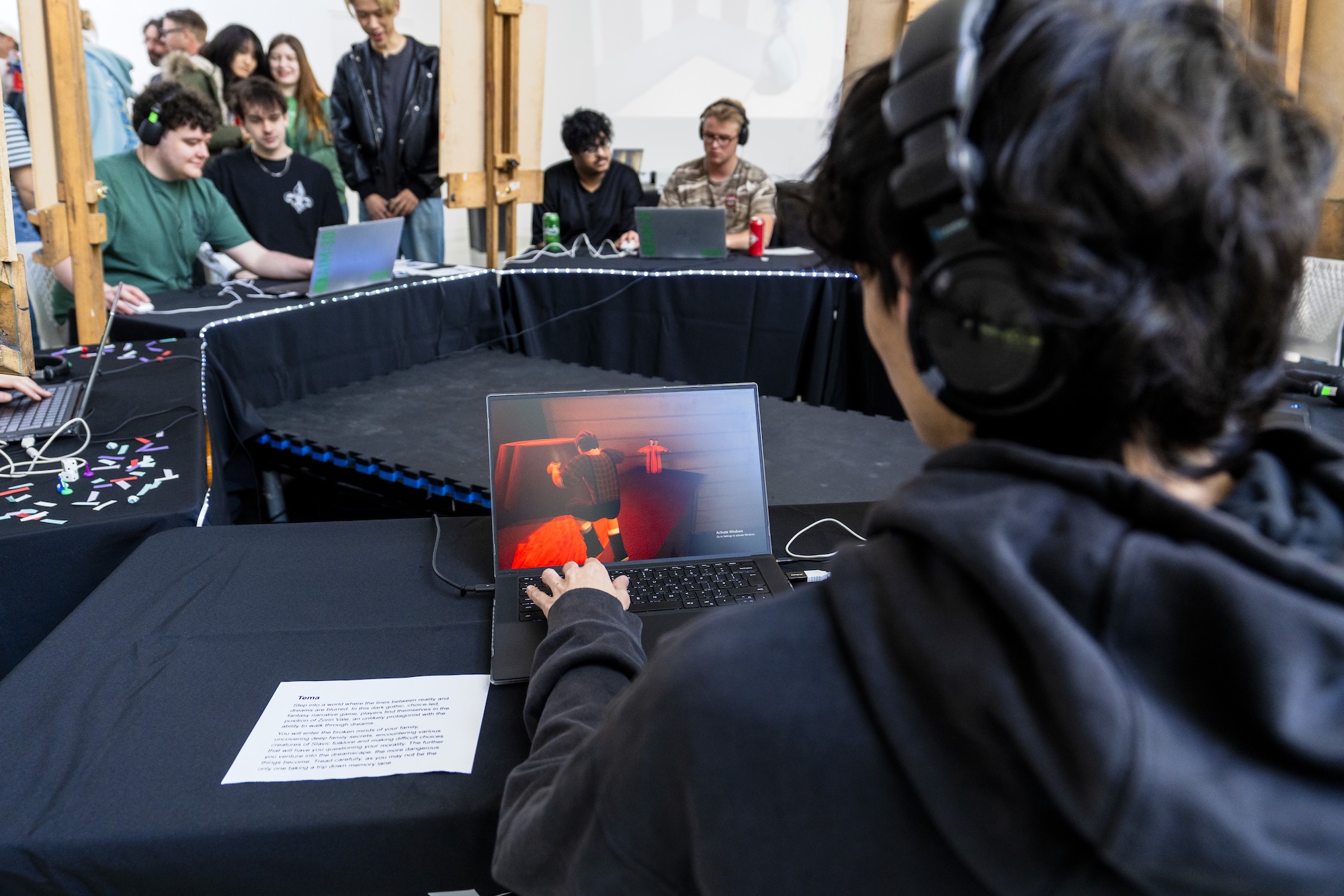 A BA (Hons) Games Art and Design student sits at a table playing a game on a laptop in front of them.
