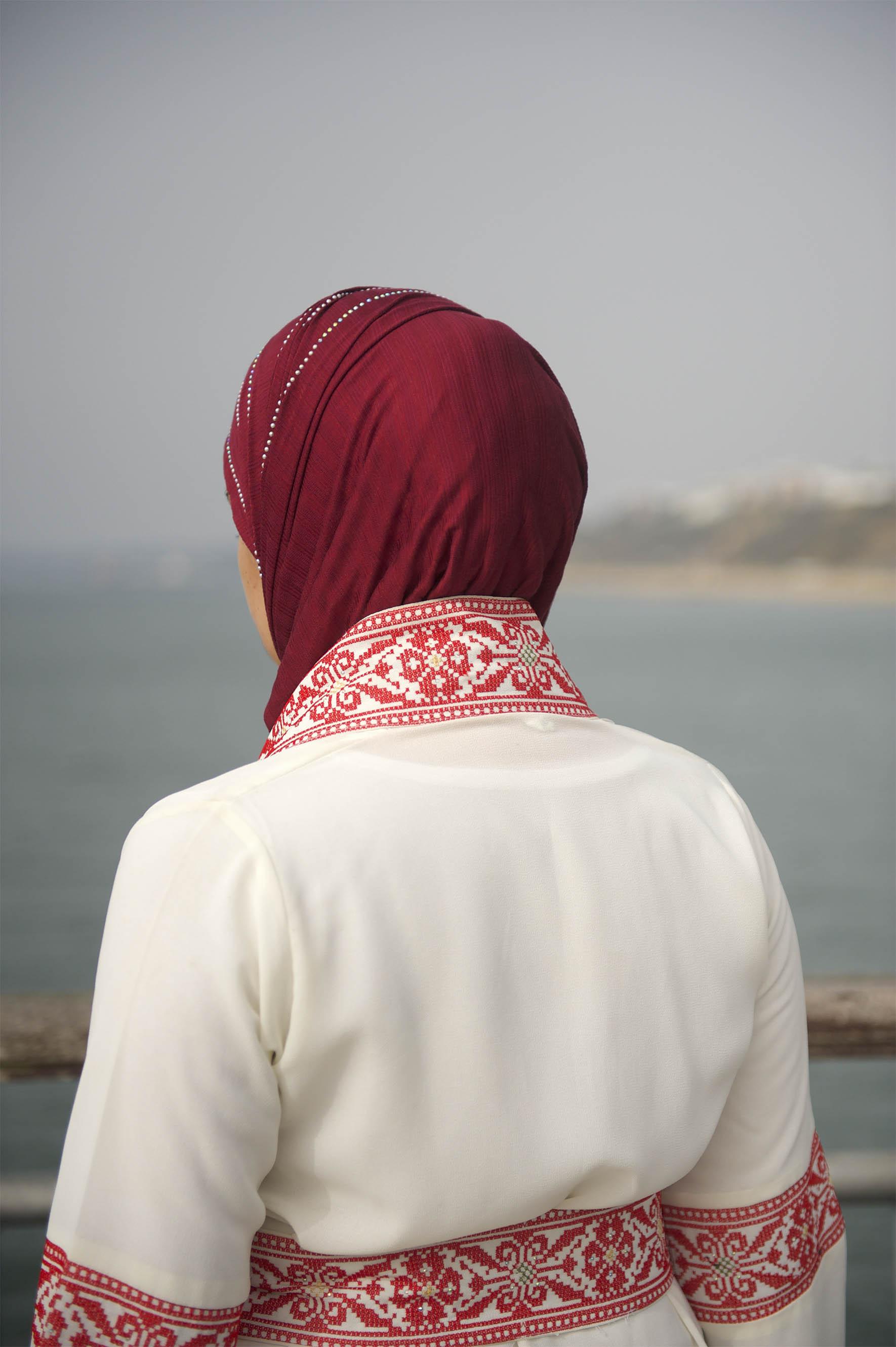 Ala'a facing away from the camera looking out to the sea, she's wearing a headscarf
