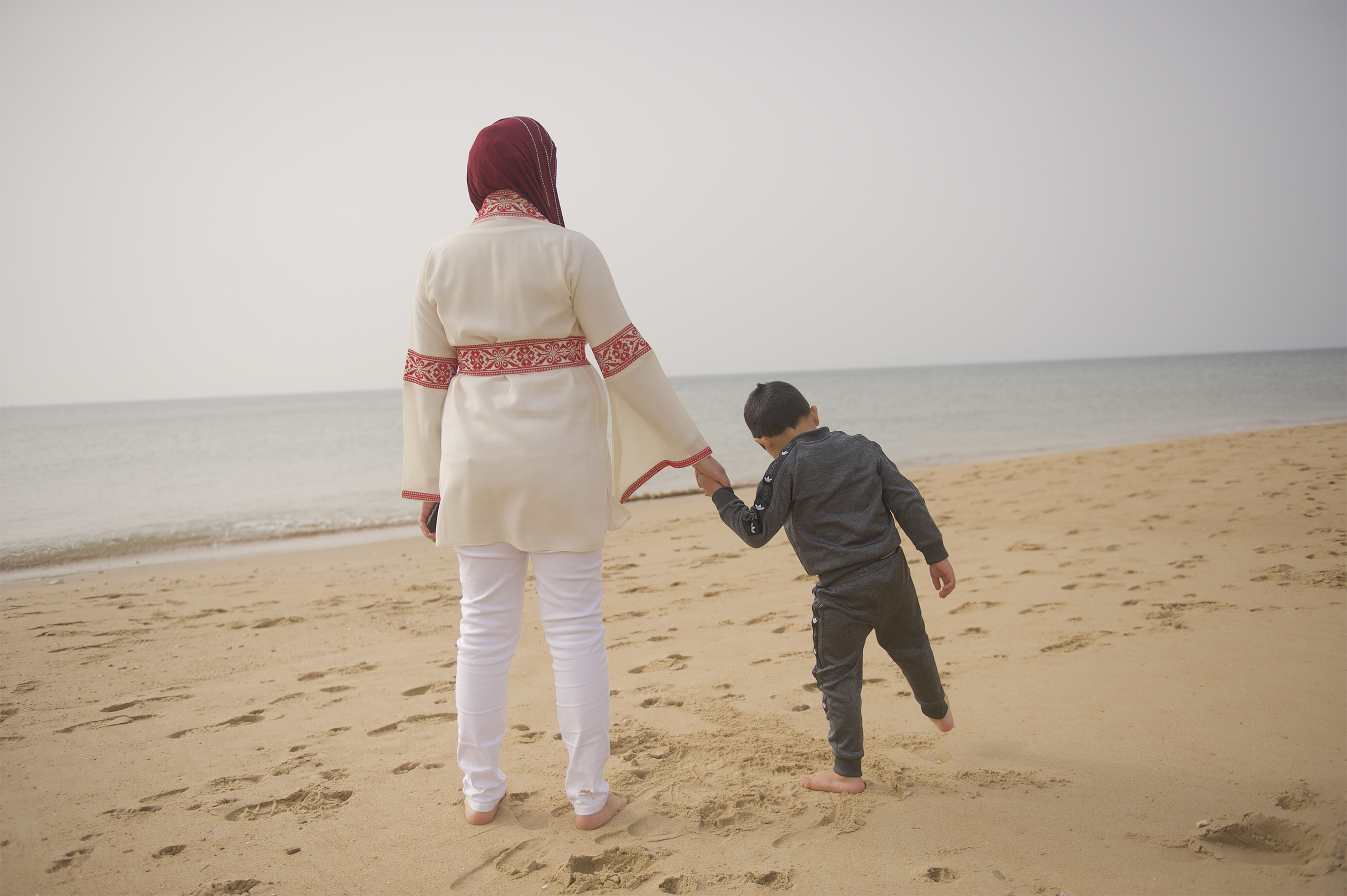 Ala'a holding hands with her child walking on the sand