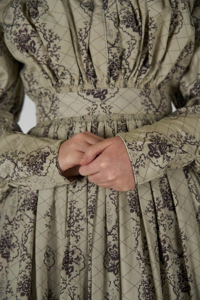 Close-up of a period-style cress with the model's hands visible.