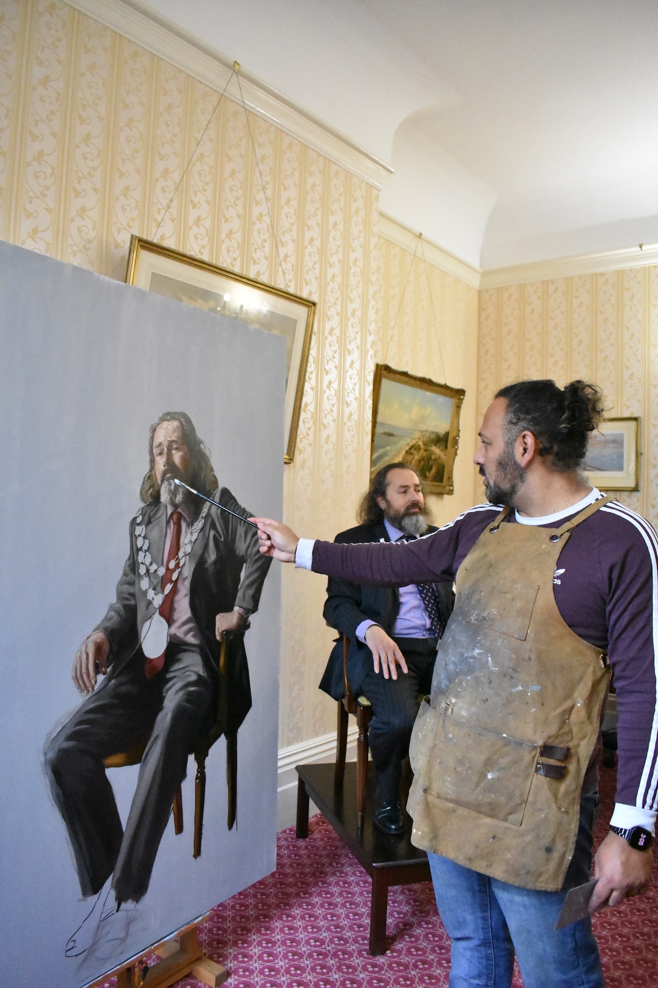 An artist in the middle of painting a full-length portrait of G Farquhar.