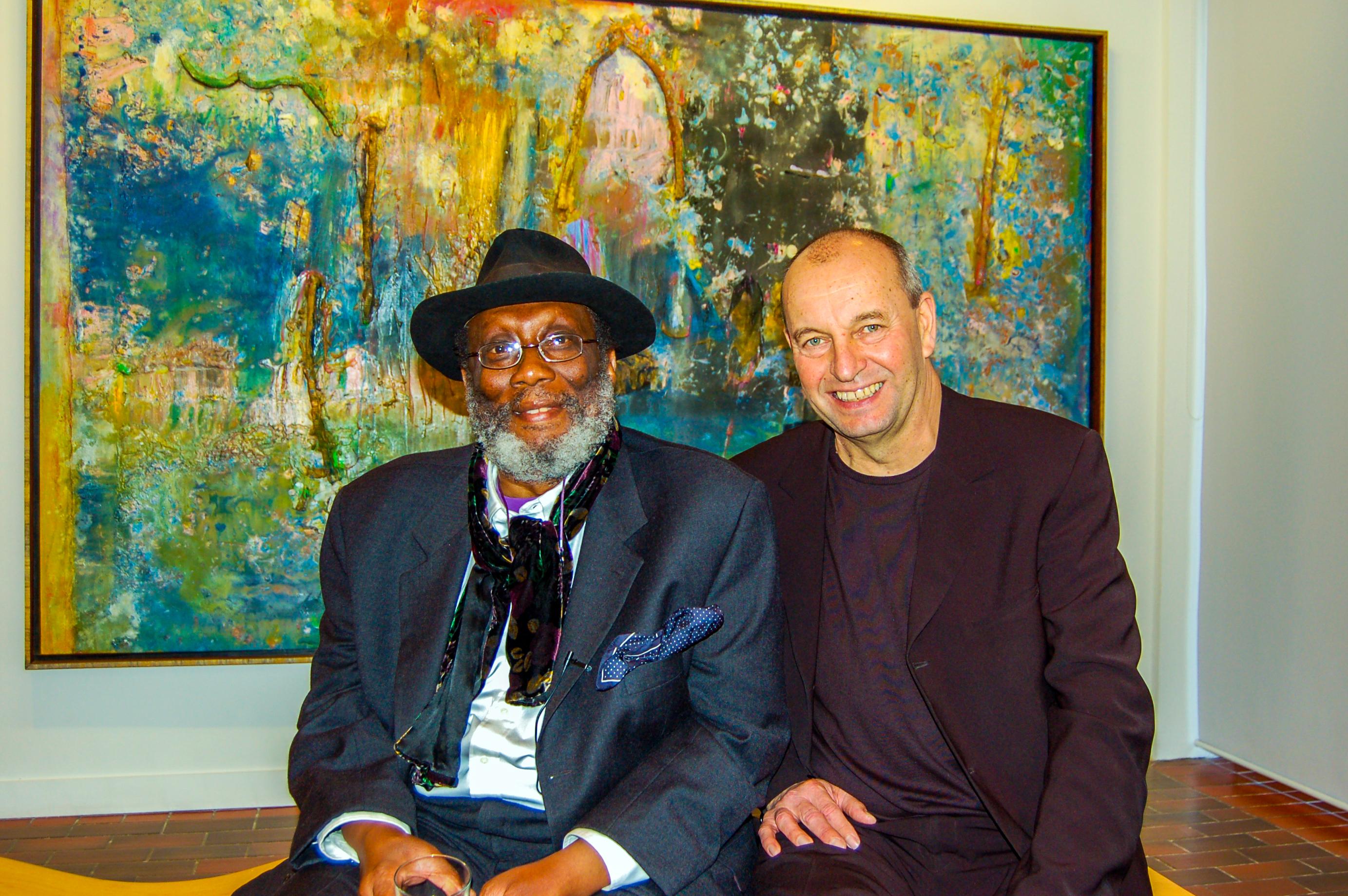Photo of Sir Frank Bowling and AUB's Jim Hunter, taken in 2008. Both men are seated in front of a large colourful painting.