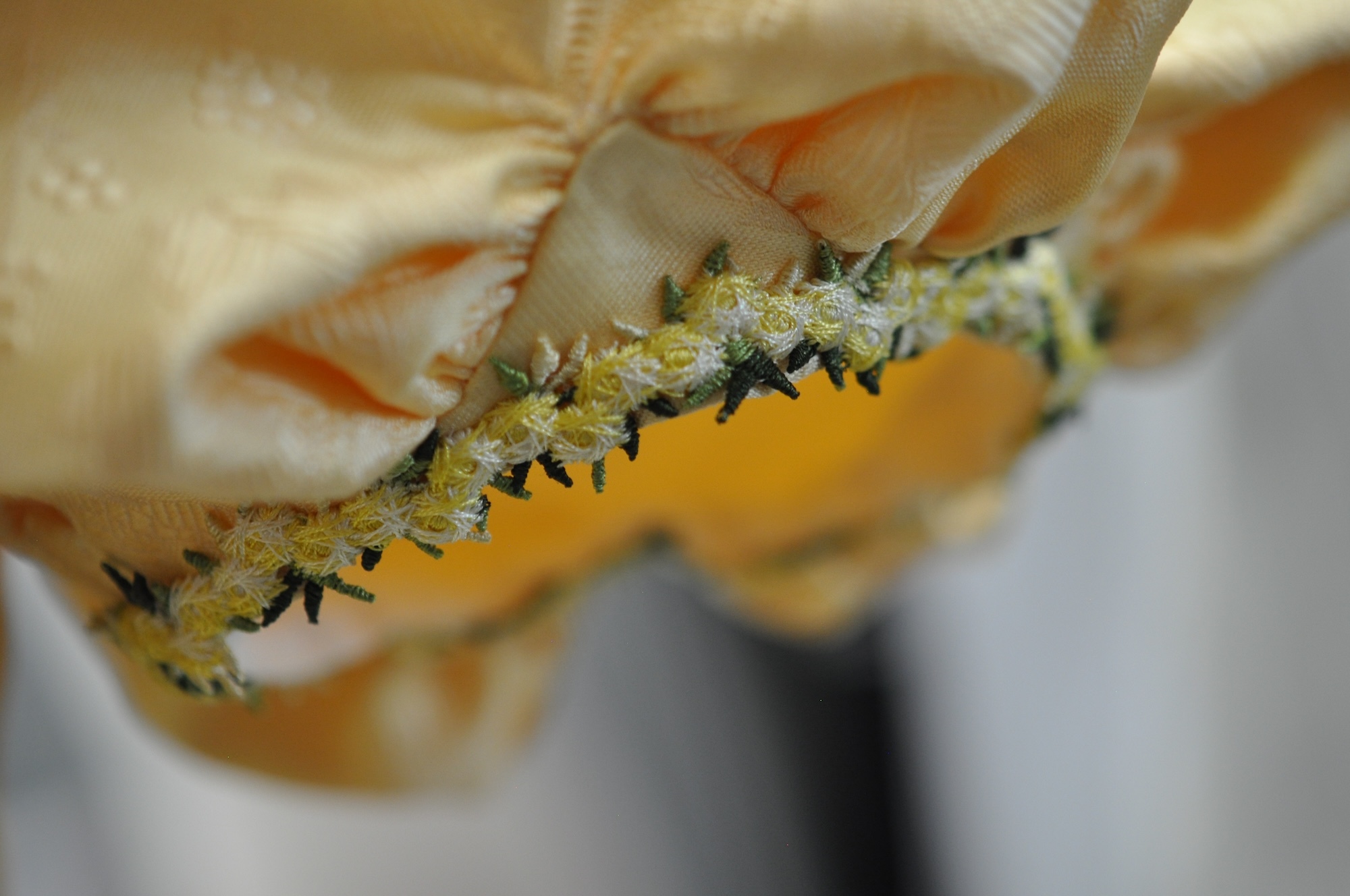 Close-up of the arm hole of a sleeve of a yellow Regency-style dress.