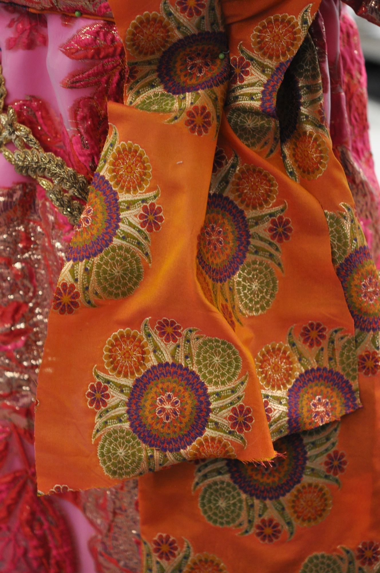 Close-up of part of a pink and orange Regency-style dress with a colourful floral design.