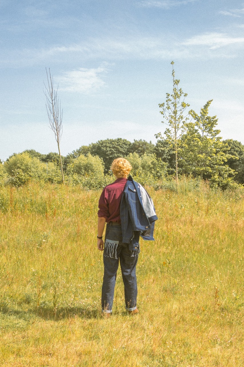 A man in a rural setting wearing 'cowboy builder'-style clothes by Victoria Saint