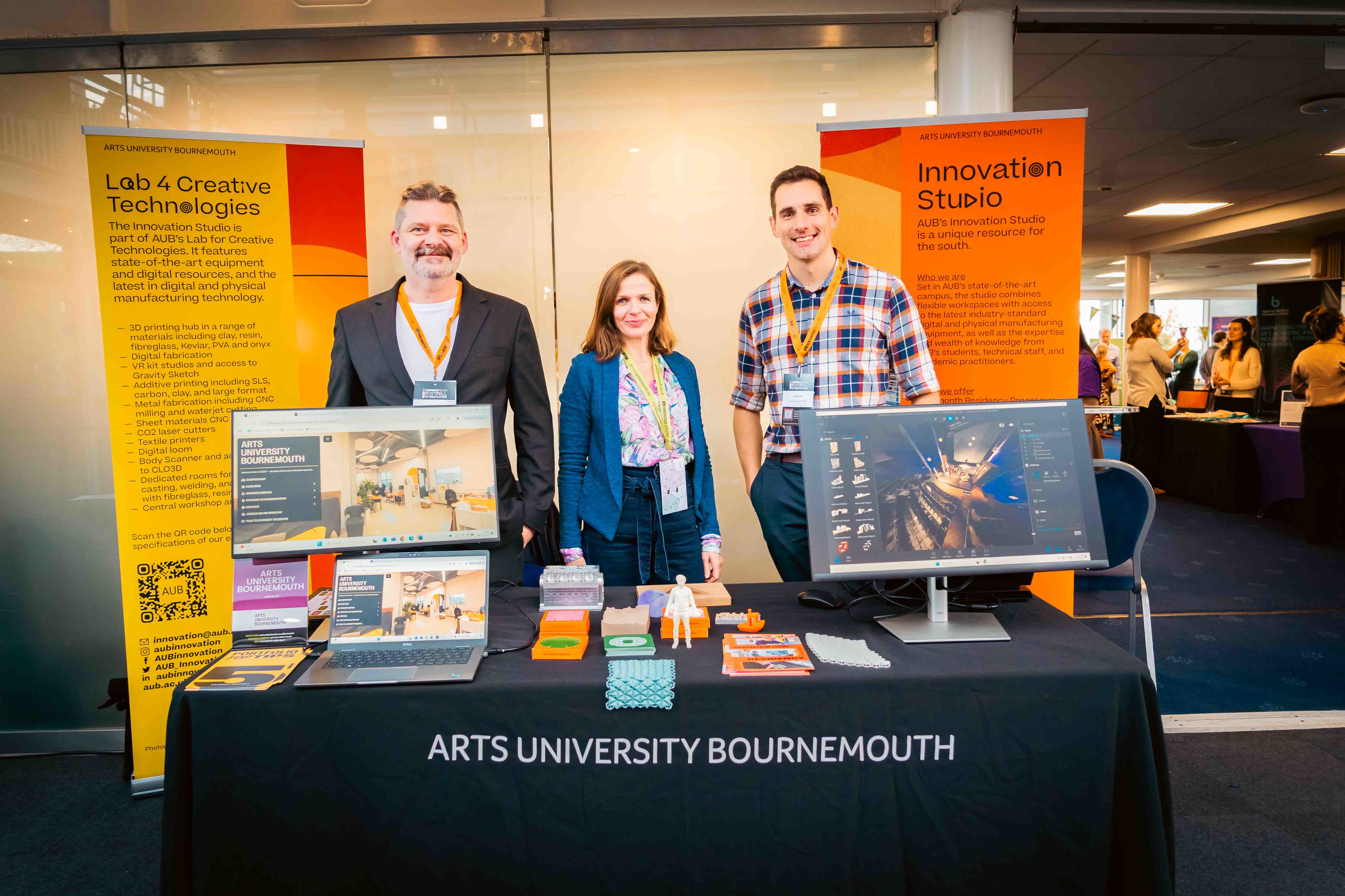 D Cox, C Trevanion and R Fanner behind the stall for the Innovation Studio, AUB at Venturefest South 2024.