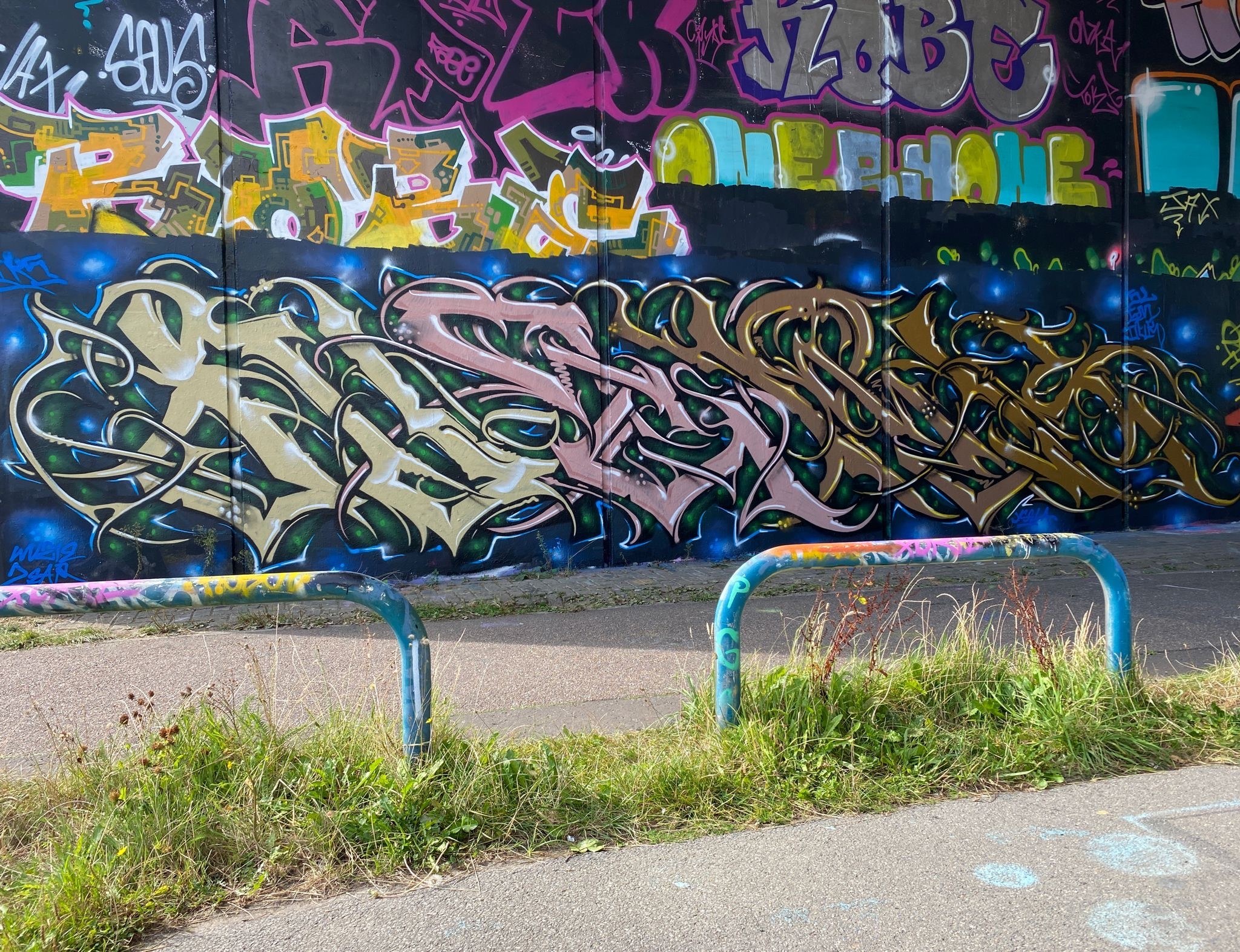 Two bicycle racks in front of a wall heavily decorated with street art.
