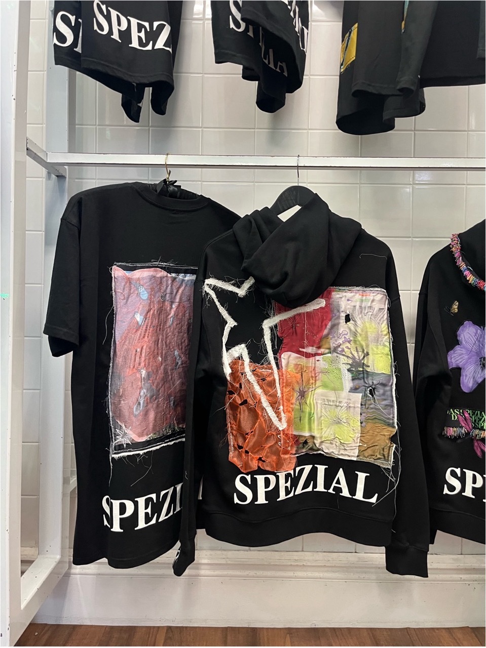 Black Das SPEZIAL hoodies on display with Emily's designs.