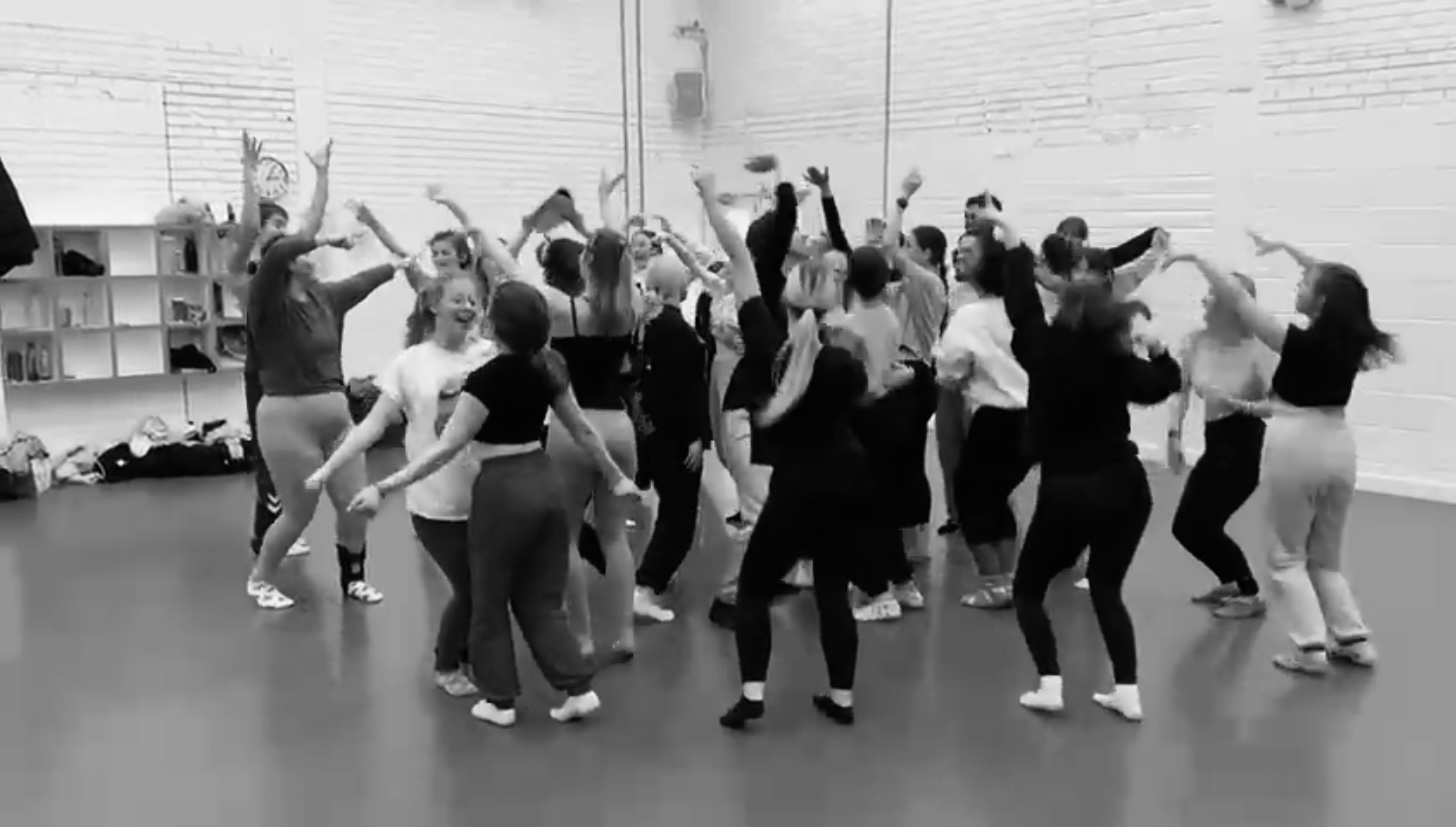 A group of people gather in a studio space and pull various poses.