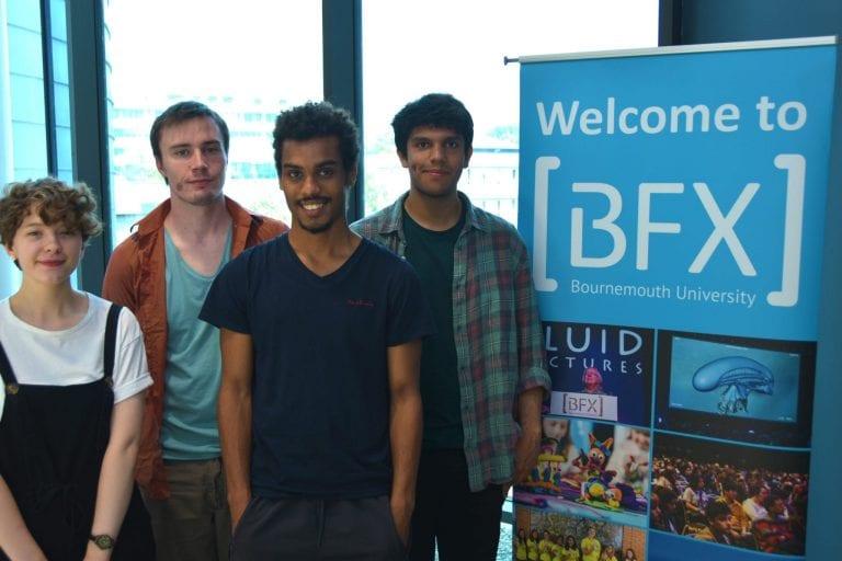 A group of four students pose for a photo while standing next to a banner reading Welcome to BFX.