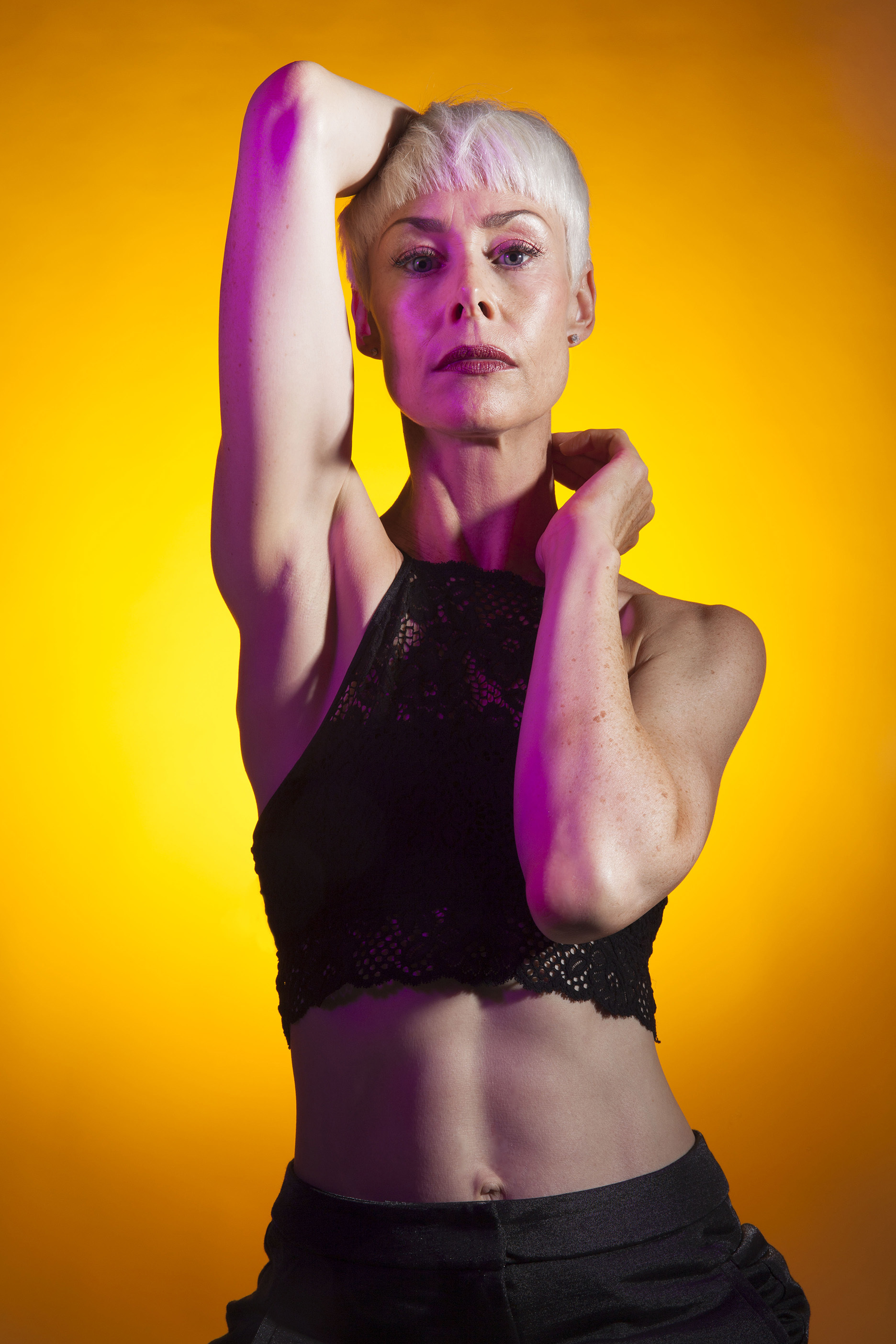 A model posing for the camera; they have their hands reaching behind their neck