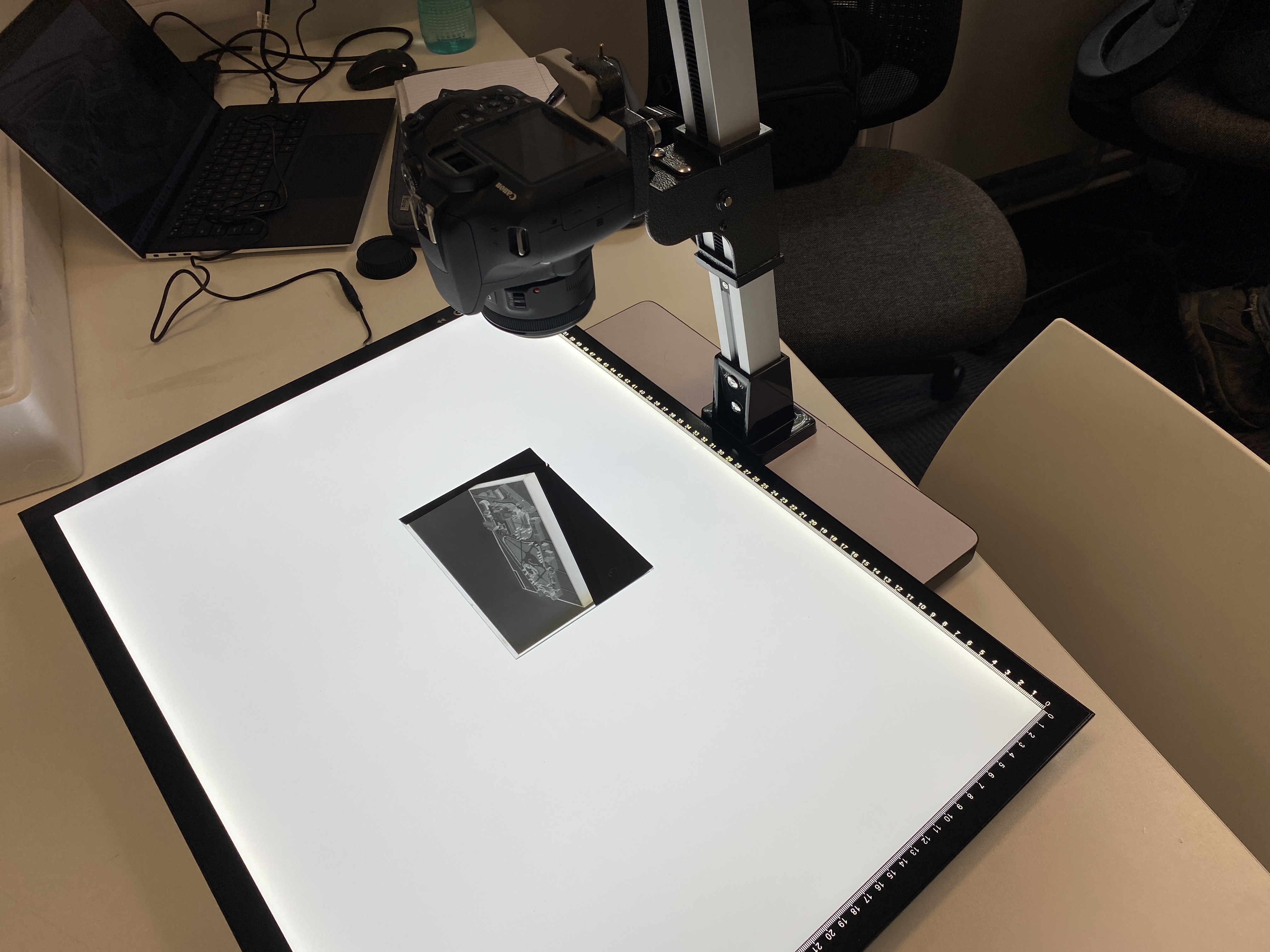 A digital camera angled directly down at a small black and white image on a large white piece of paper.