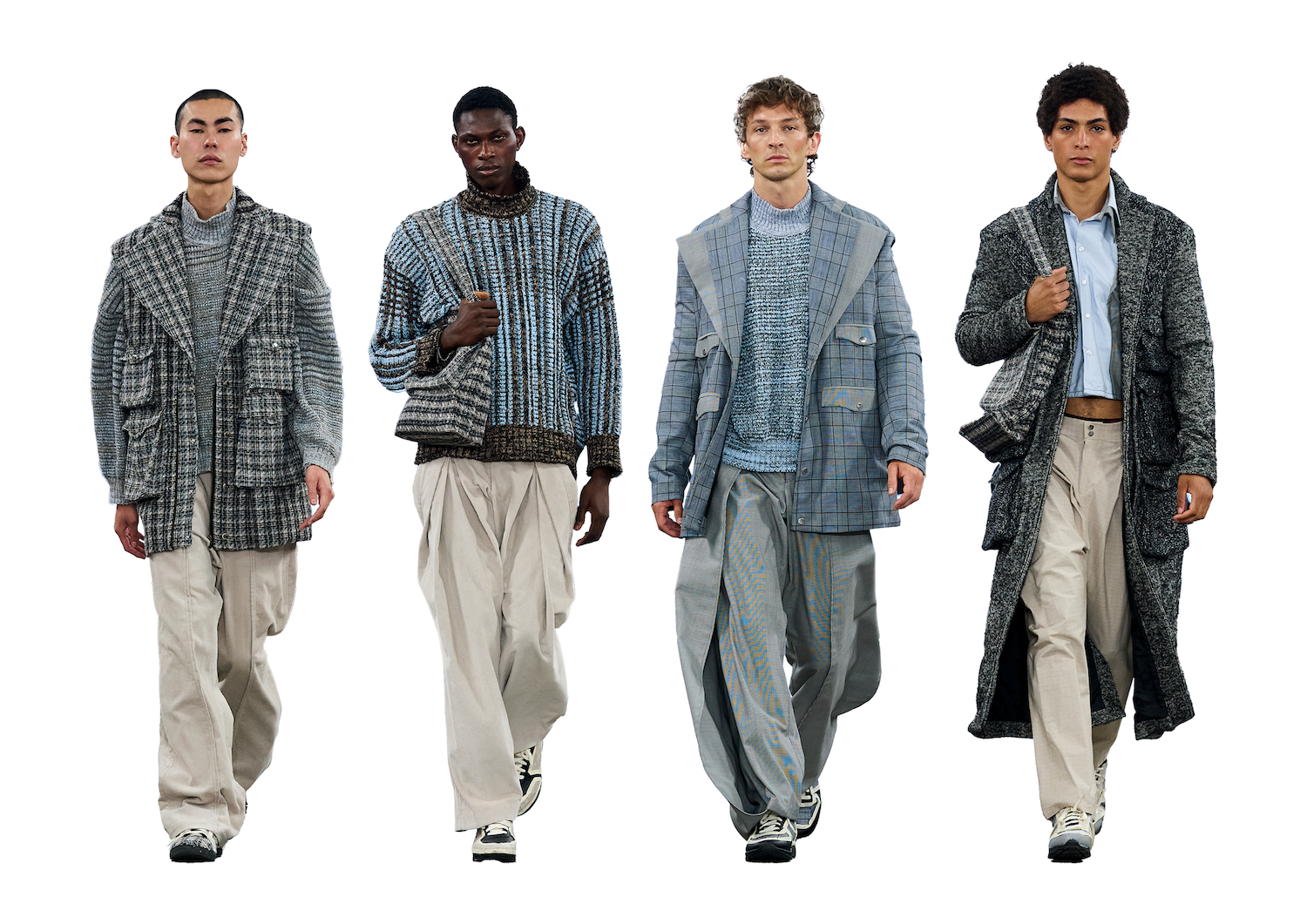 Four male models are walking side by side, each wearing oversized outerwear. The first model on the left is in a grey checked coat, followed by a model in a patterned sweater and beige trousers. The third model wears a light blue jacket and slacks, and the last model has a dark coat and light trousers.