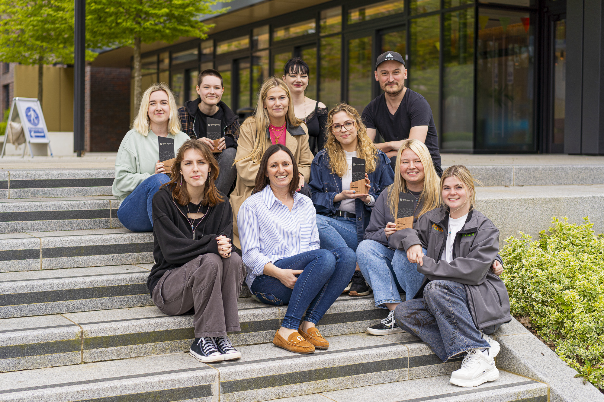 BA (Hons) Visual Communication students and EPM Head of Digital F Griffiths posing for a photo on the front steps of Campus Halls, AUB Campus.