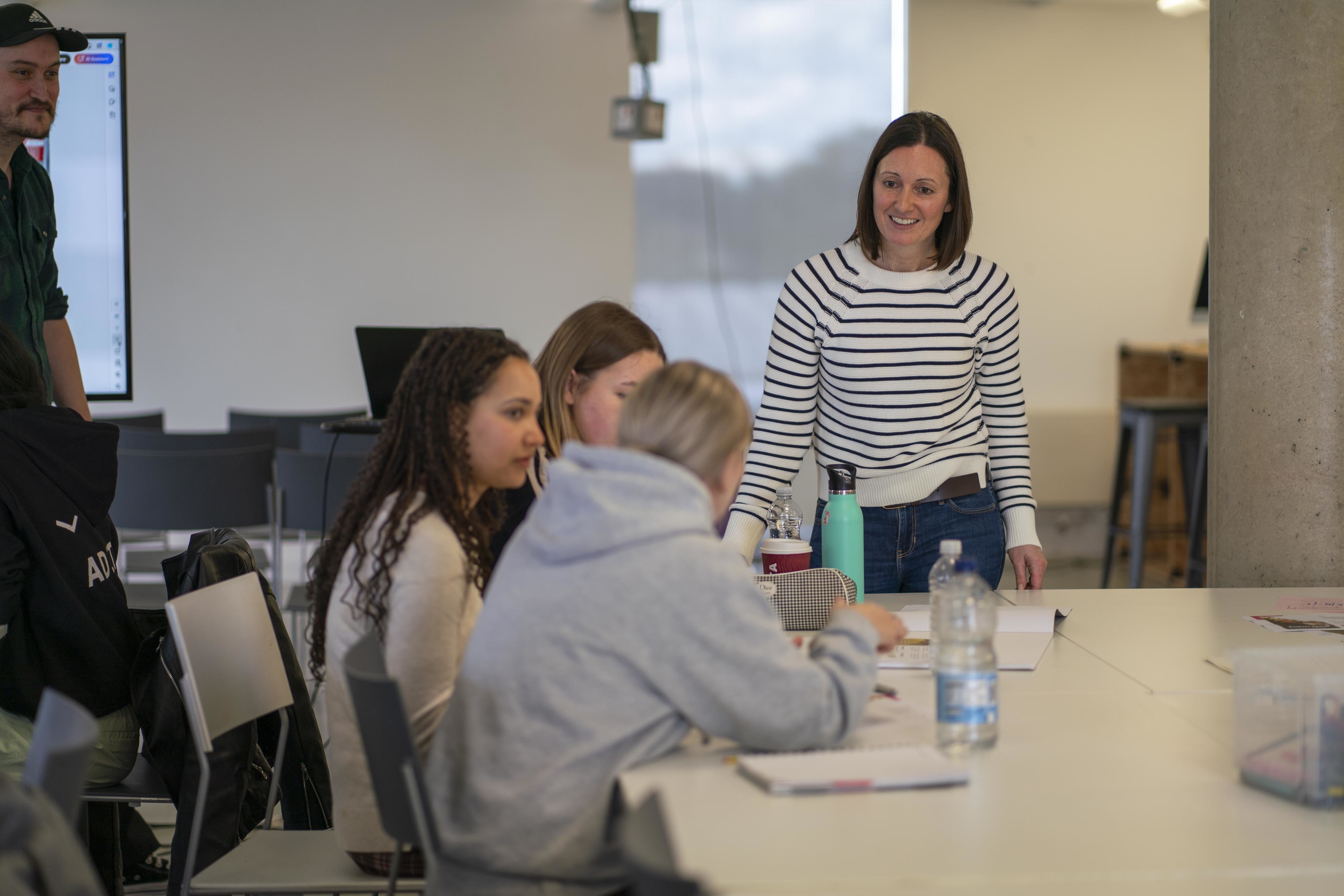 F Griffiths, EPM Agency's Head of Digital, talks with three BA (Hons) Visual Communication students during a workshop.