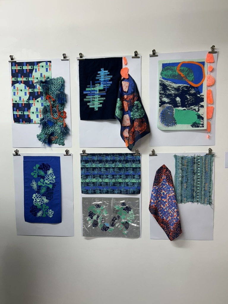 A selection of six pieces of BA (Hons) Textiles Design work with samples and designs displayed on a white gallery wall