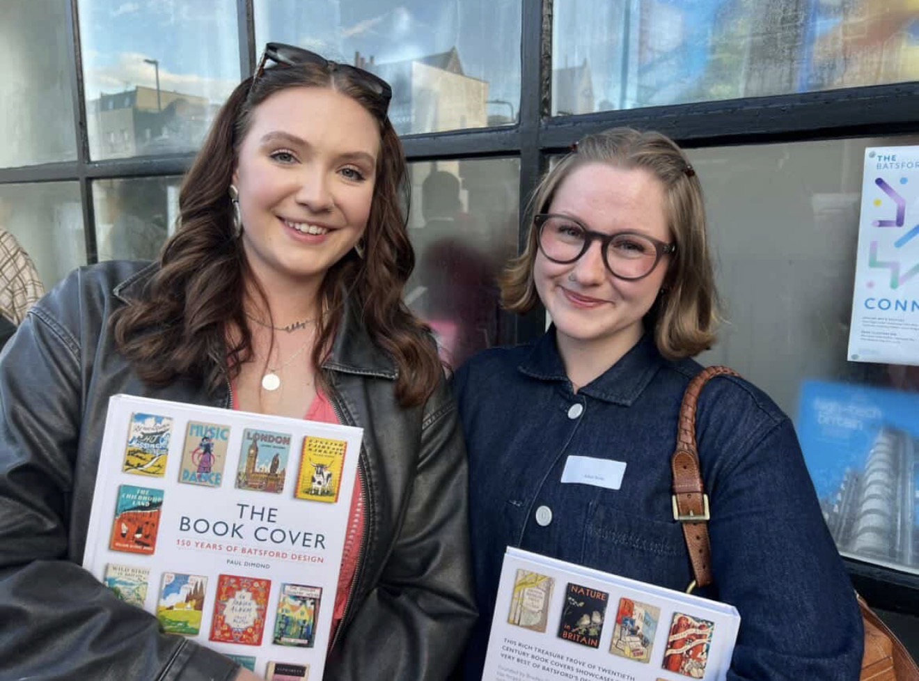BA (Hons) Textiles Design students E Webber and A. Rose pose for a photo outside a bookshop, holding copies of "The Book Cover".