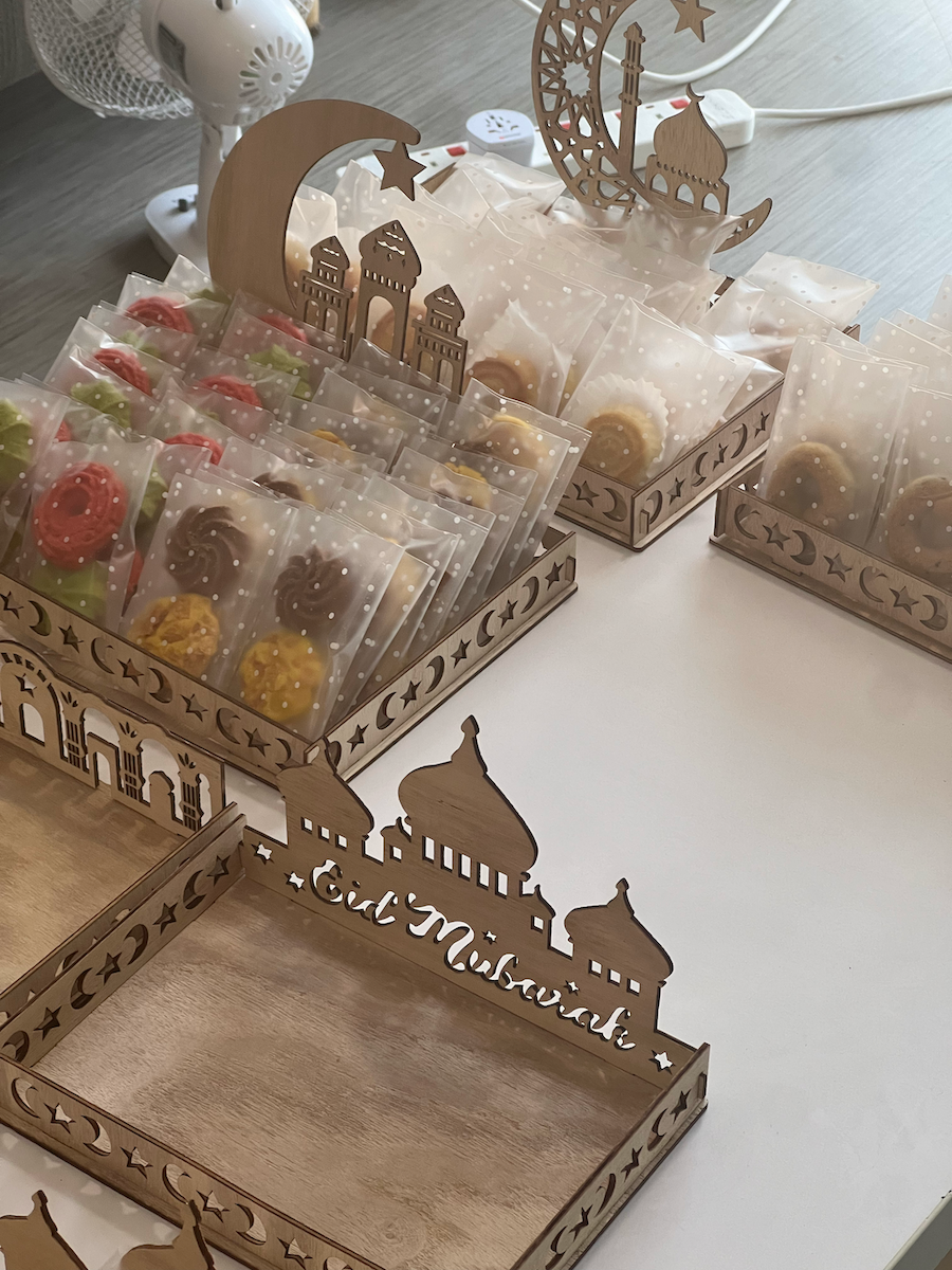 Close-up of sweets in plastic packets, sitting on display in boxes with ornate Eid Mubarak designs.