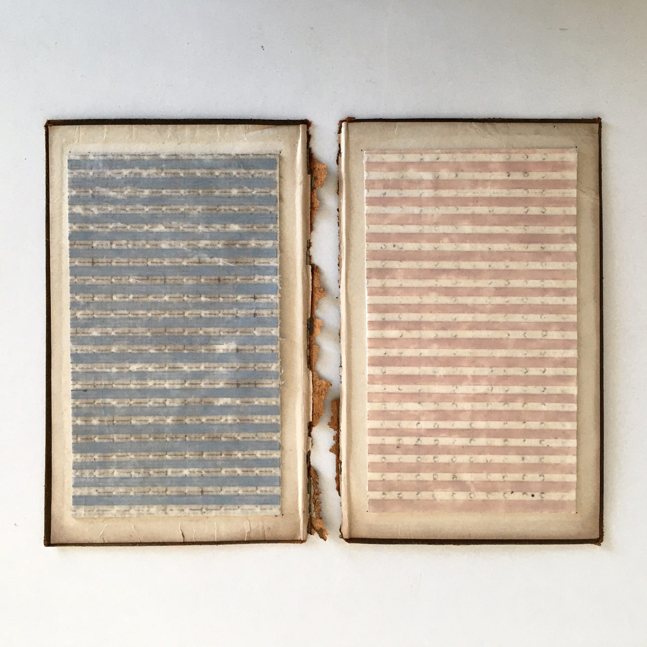 Two halves of an old document that appears to have fallen apart. The right-hand side shows a faint, handwritten code.