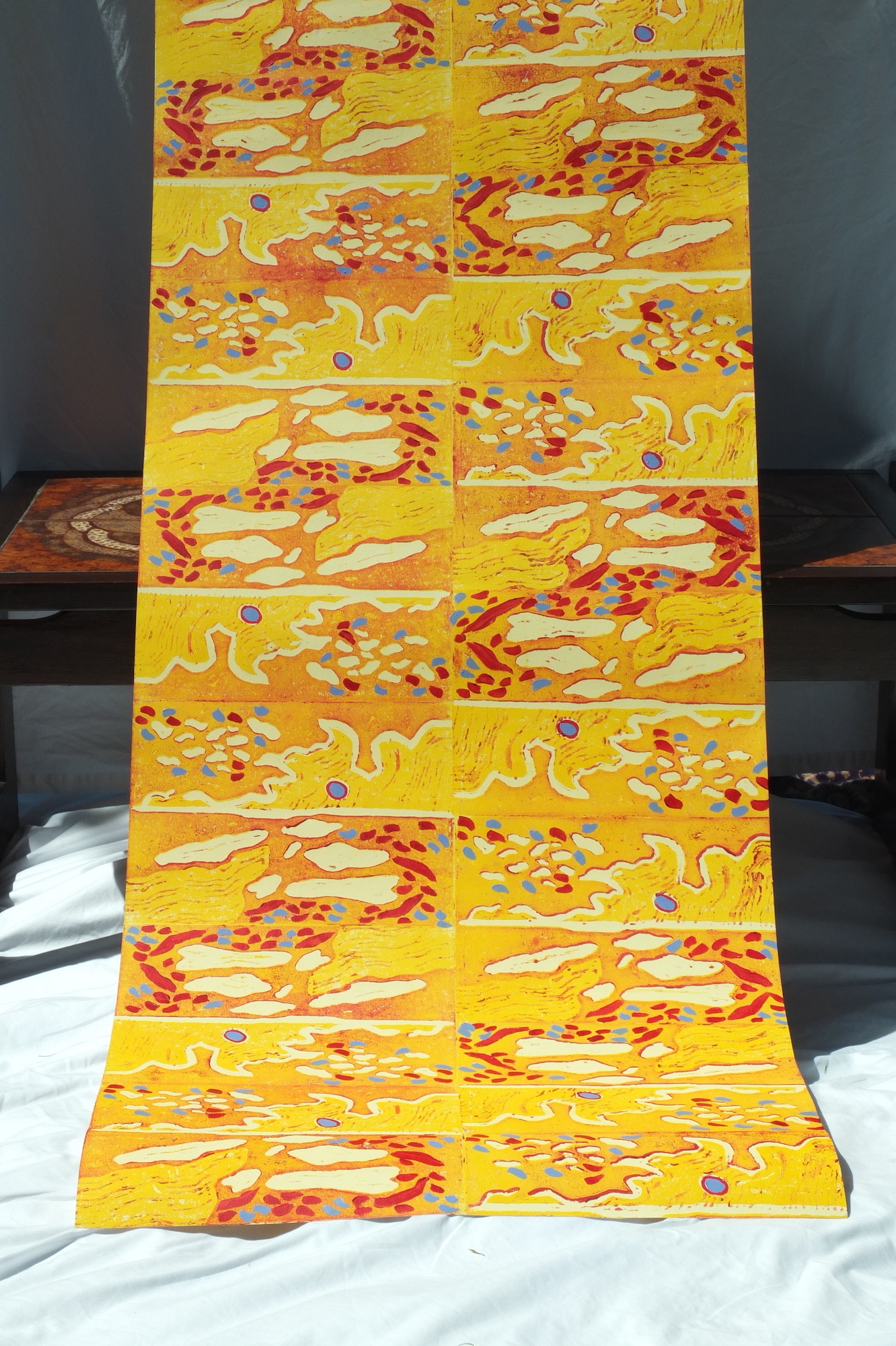 A long piece of yellow and orange abstract-patterned fabric hanging down onto the floor.