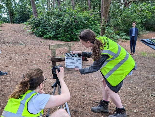 Ella Shipley in a film set in the woods, wearing a high-vis.