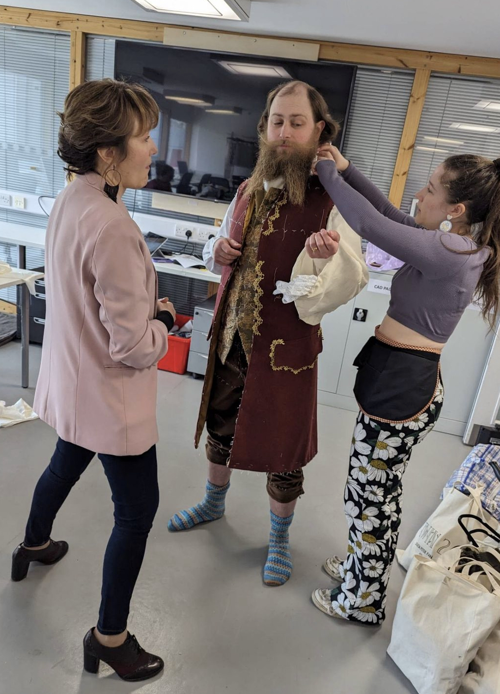 Model being clothed in a Captain Hook costume with a red and gold-embroidered overcoat.