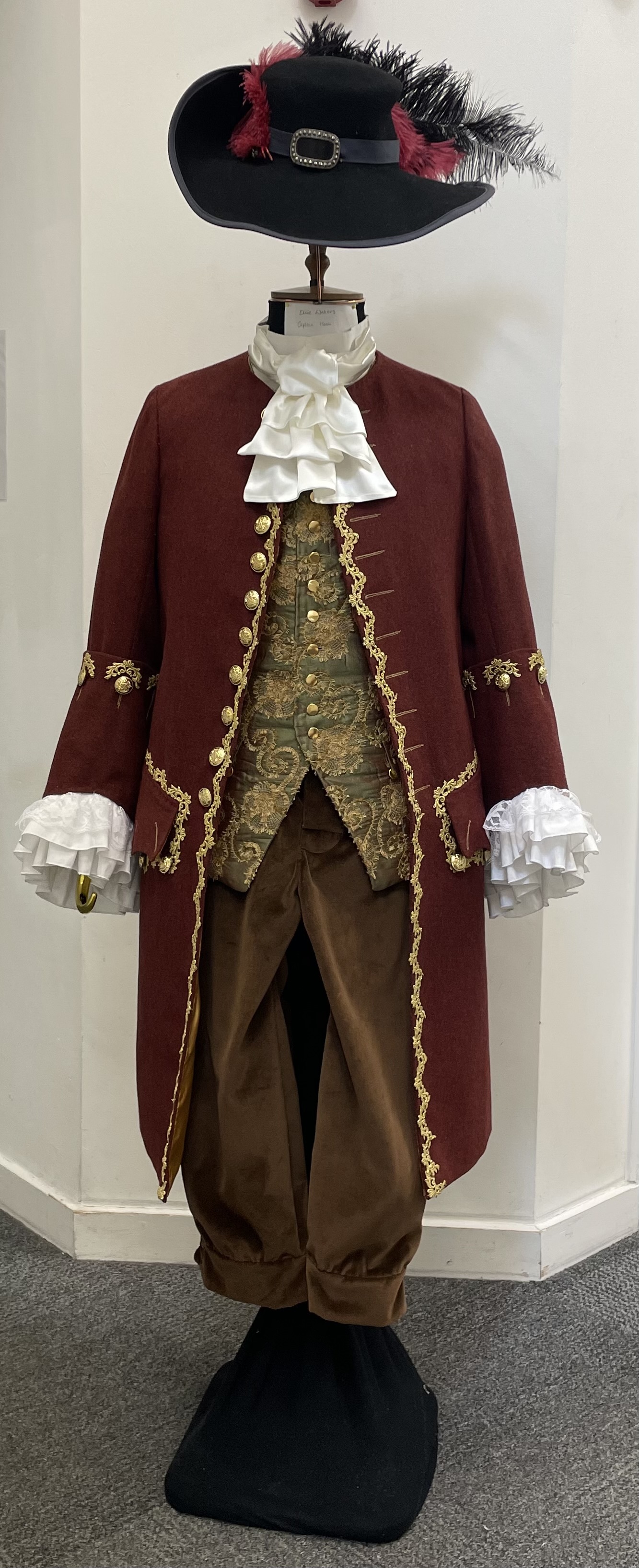 Red and gold Captain Hook costume with a feather hat and ruffles on a mannequin, white background.