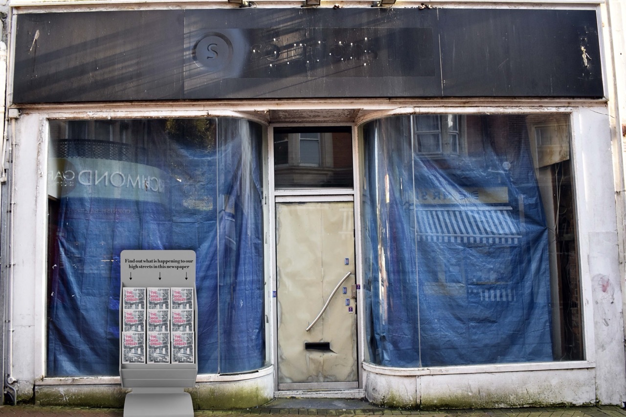 Abandoned shop front with blue tarpaulin and a newspaper stand about what's happening to our high streets.