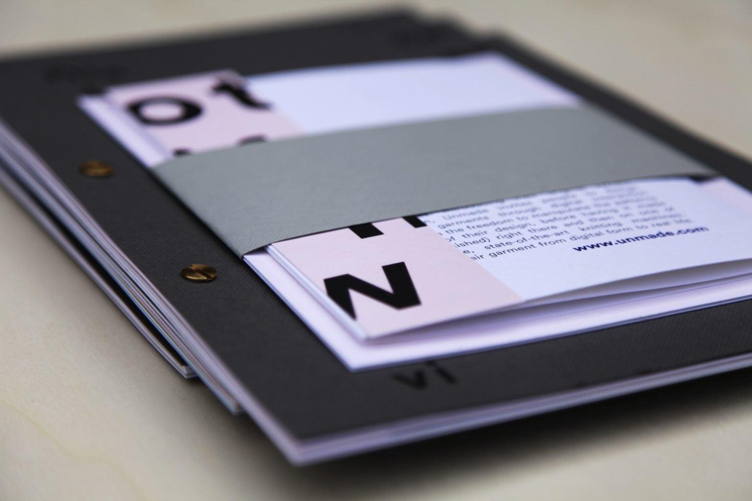 Close-up of paper branding materials in a black folder lying on a table.