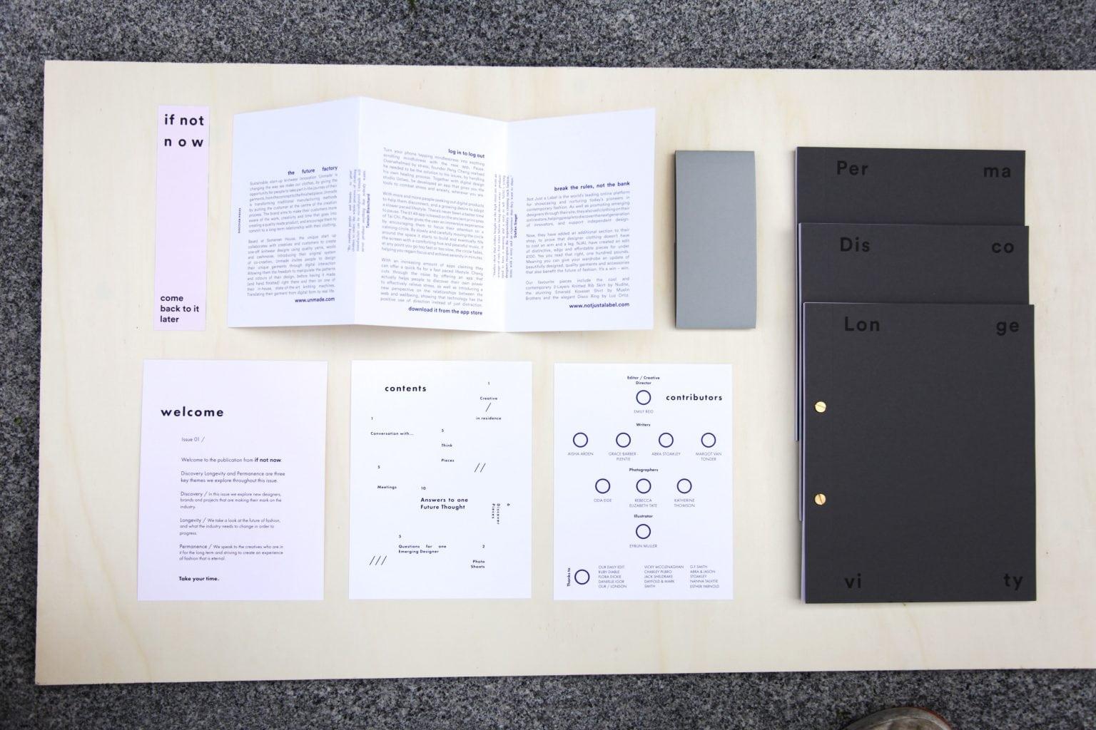 Various pieces of paper branding materials and three black folders laid out on a large sheet of paper.