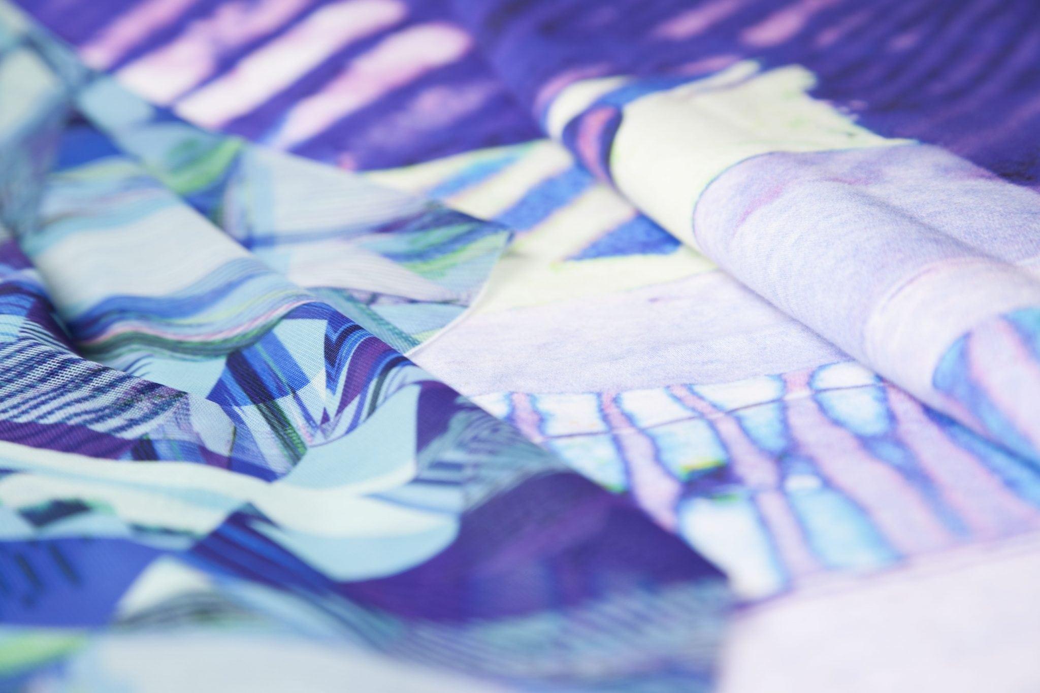 Pieces of thin, colourful fabric lying on a plain surface.