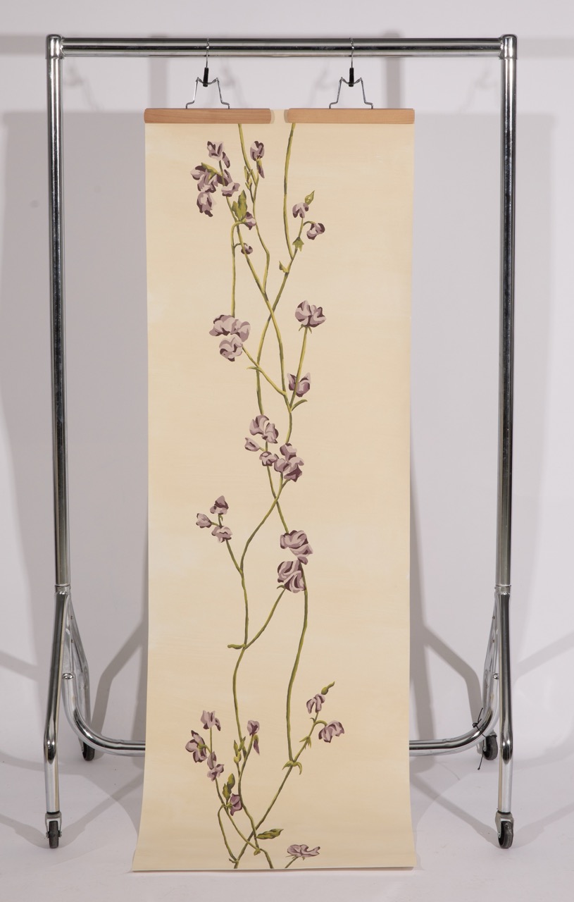 A floral artwork featuring various purple sweet pea flowers on a cream-coloured background, displayed on a hanging paper scroll. The design includes delicate green stems and leaves, extending vertically down the centre of the scroll.