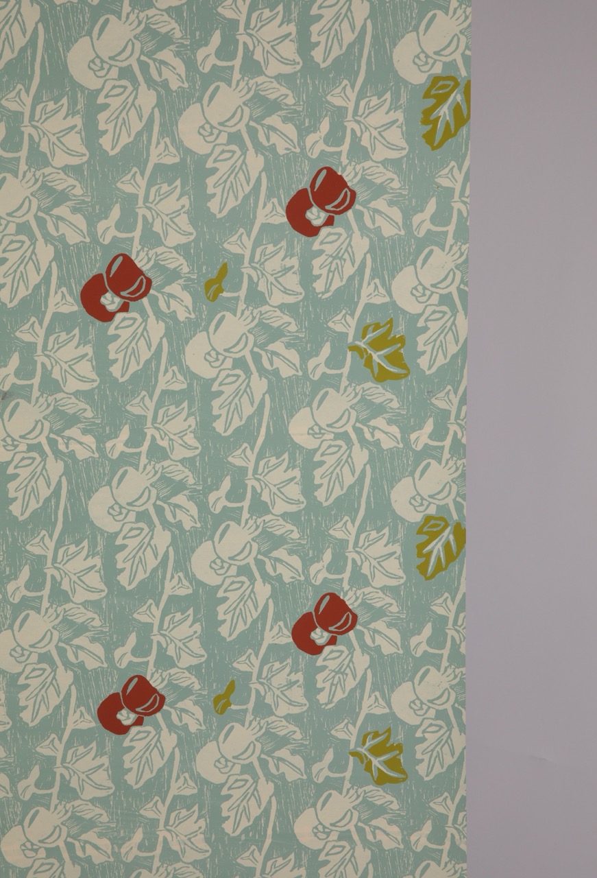 A fabric panel featuring a repeating pattern of stylised flowers and leaves in white, with red and green accents on a light blue background. The design is bold and graphic, suitable for various textile applications.