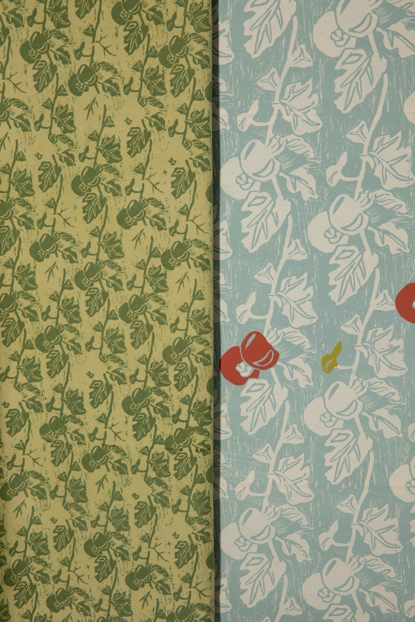A split image showcasing two distinct patterned wallpapers. The left side features a green background with leaf and vine motifs, while the right side displays a blue background adorned with stylised apples and leaves in white and red.