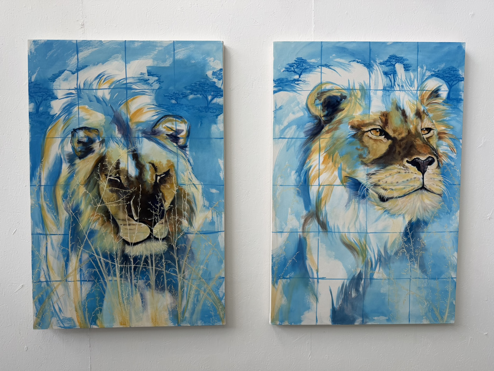 Two paintings of lions displayed side by side. The left painting features a lion's face with a blend of blue and gold tones, while the right painting presents a profile view of a lion with similar colouration, both rendered in an impressionistic style.