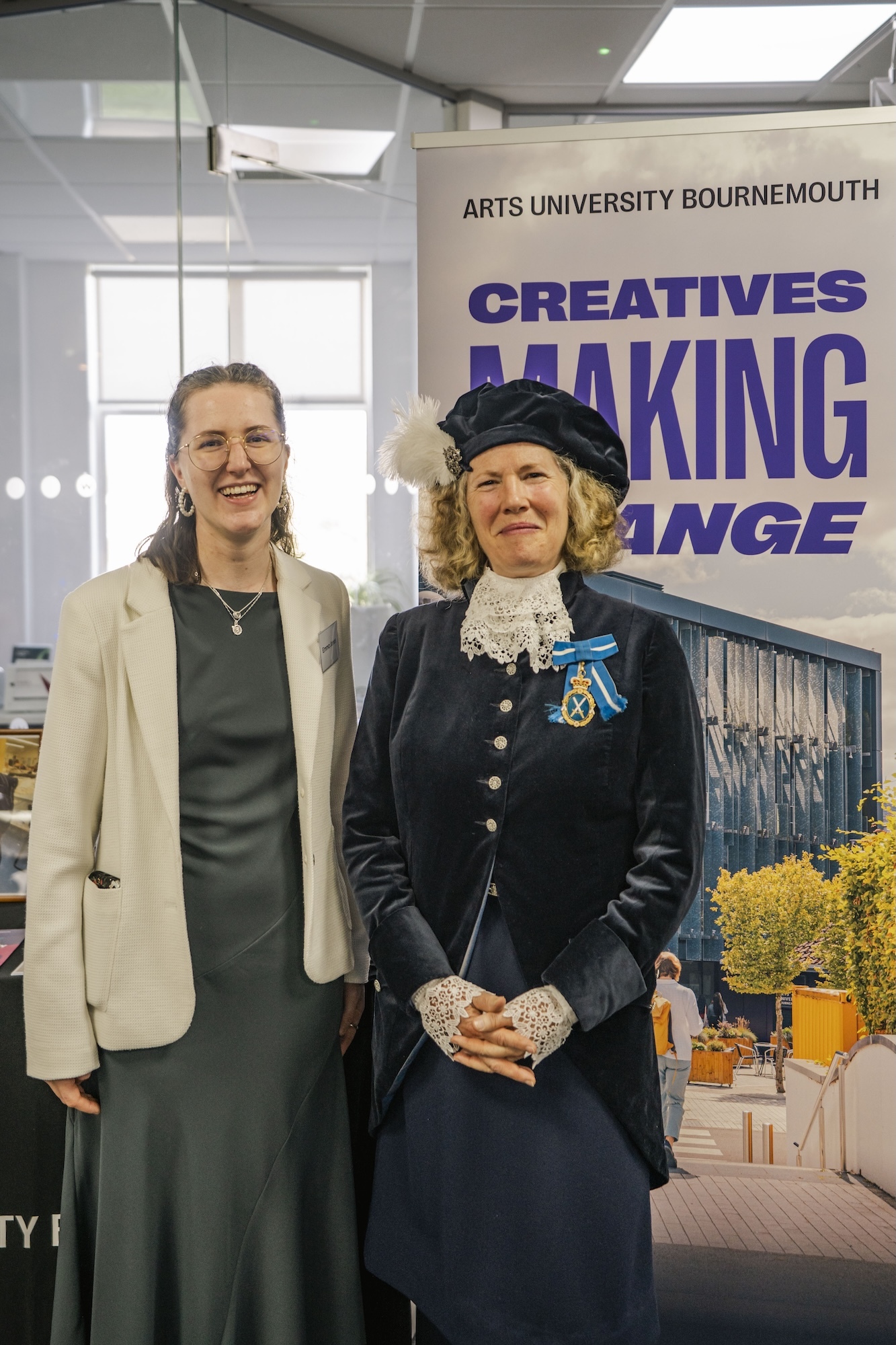 BA (Hons) Costume student E Jones with Dorset High Sheriff H Conibear posing in front of an Arts University Bournemouth "Creatives Making Change" banner.