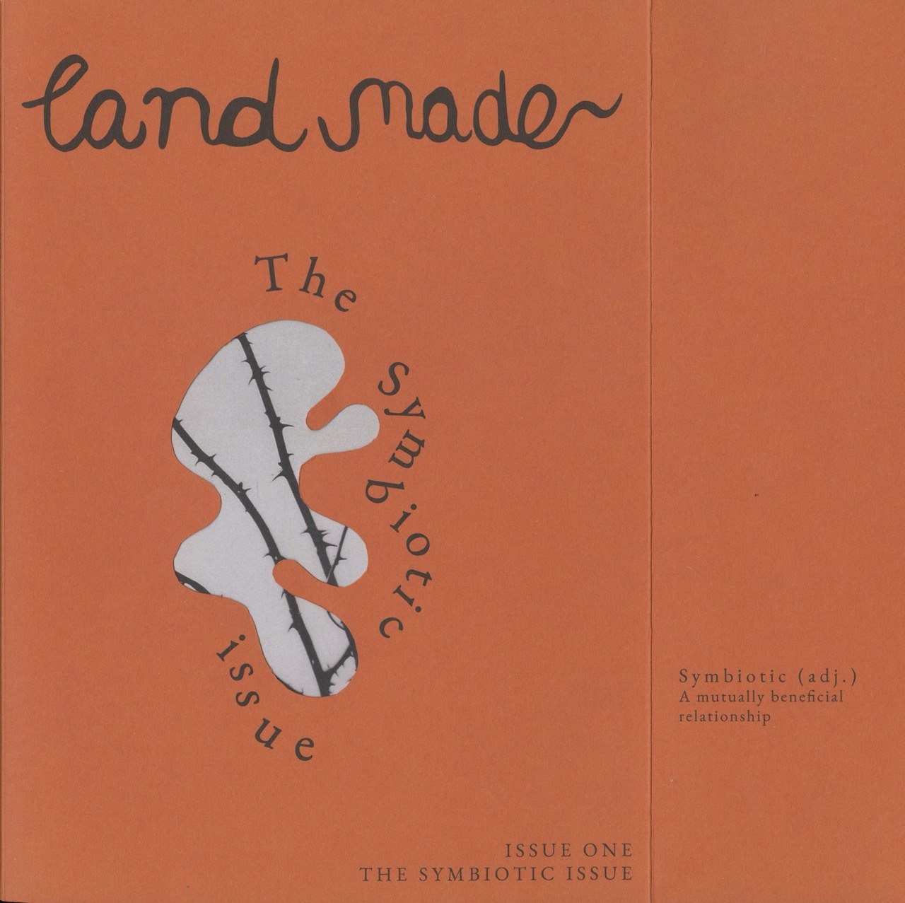 Orange magazine cover with handwritten "landmade" title, white abstract shape with black line, curved text reading "The Symbiotic Issue"