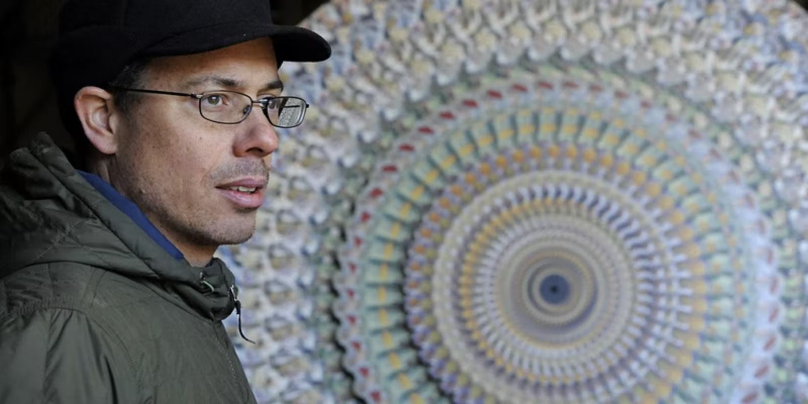Headshot of E Dyer standing next to his artwork.
