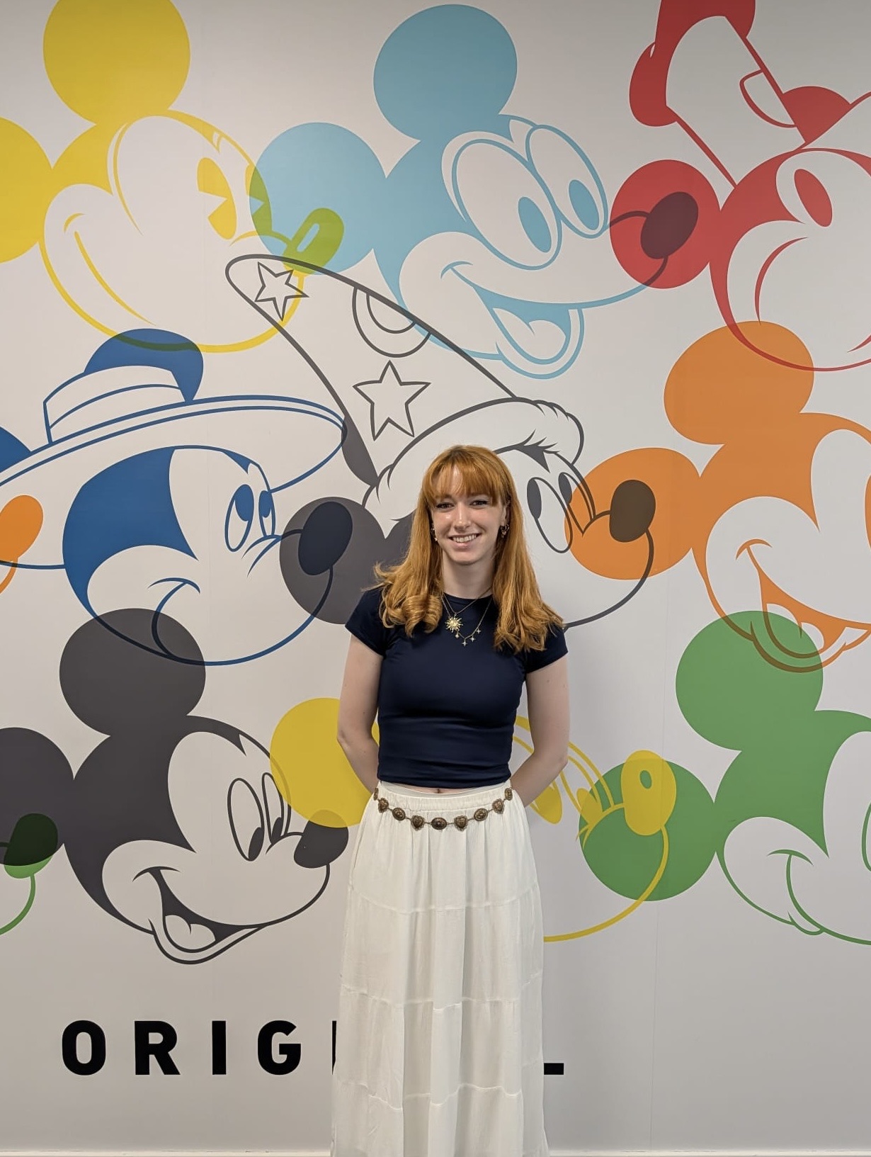 E Jarvis stands in front of a colourful mural of Mickey Mouse faces and hats, with the word “ORIGINAL” partly visible at the bottom.
