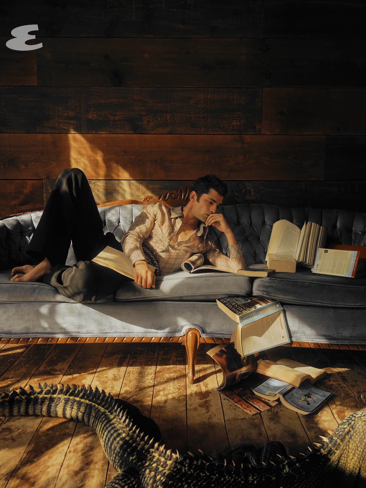 A model posing on a light blue sofa in the light with opened books.