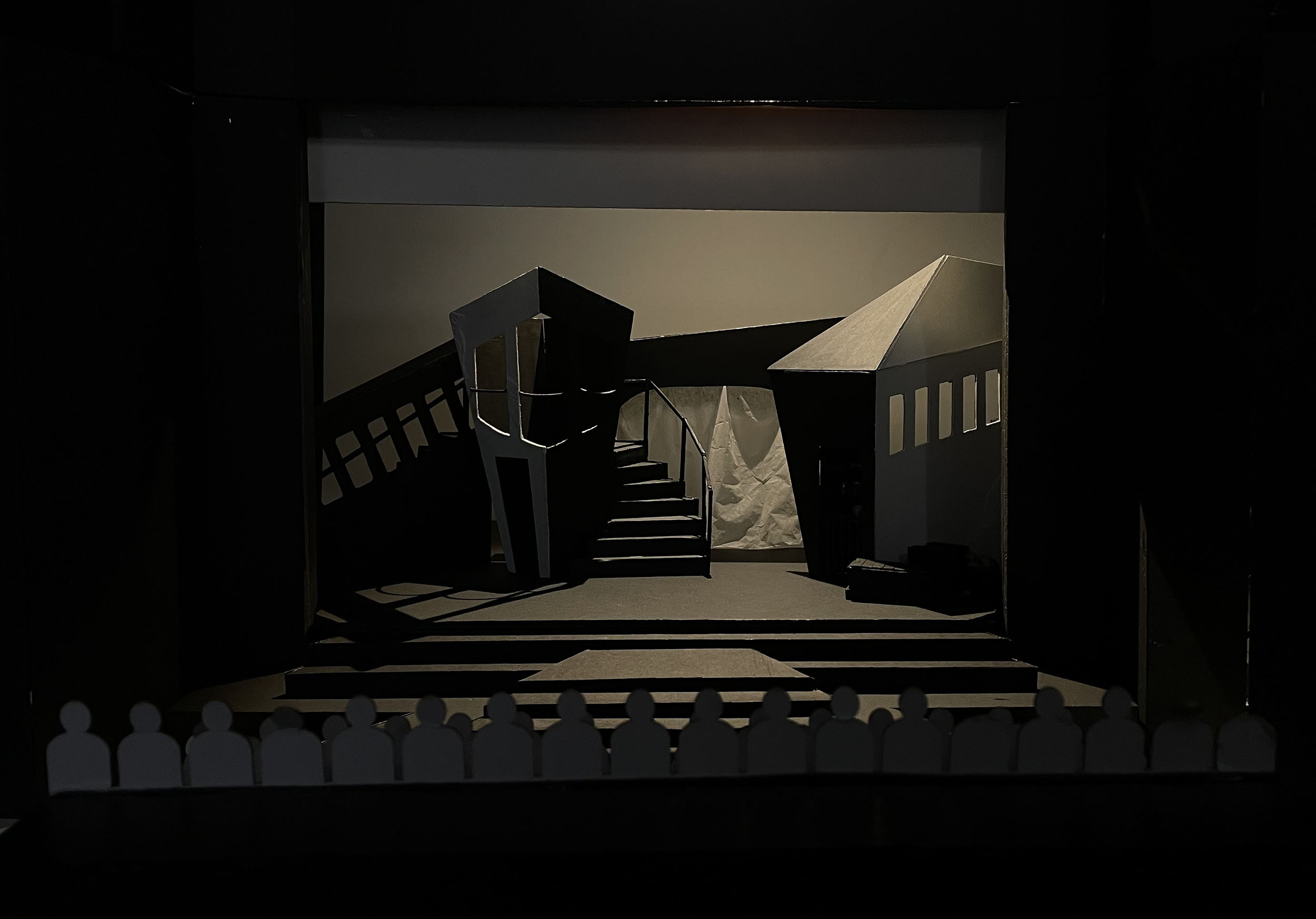 Theatre stage set with angular geometric structures, dark staircase, white triangular sail-like element, and warm beige backdrop.
