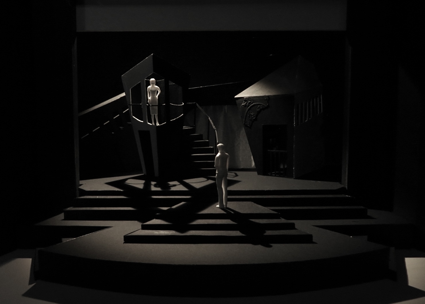 Dark interior with curved staircase, two figures in white clothing, dramatic lighting creating strong shadows on checkered floor pattern.