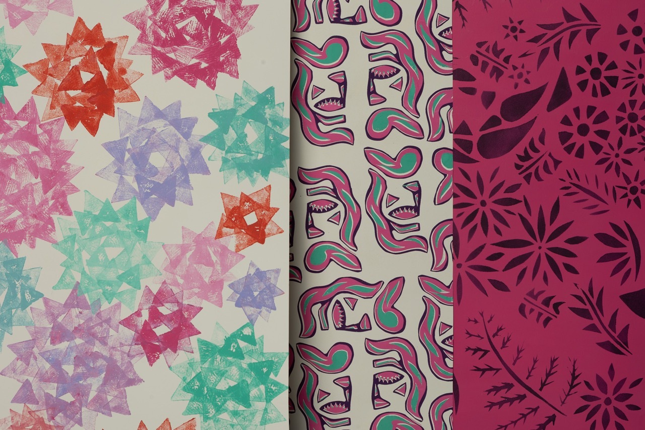 Three decorative paper patterns: left shows multicoloured geometric stars, centre displays wavy ribbons in pink and green, right features dark pink floral motifs.