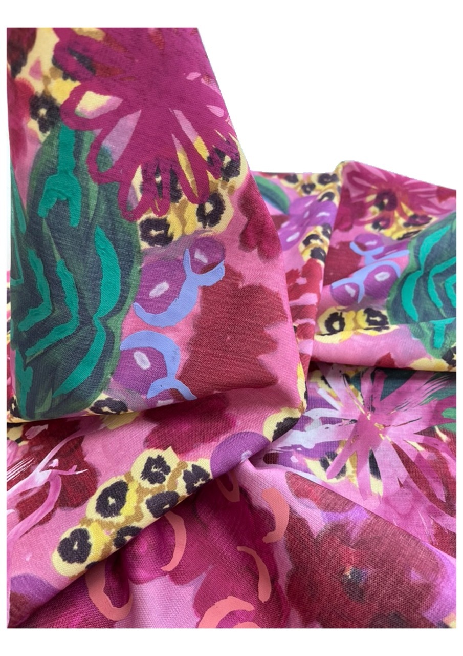 Folded fabric with vibrant floral pattern in magenta, pink, yellow, and teal. Large blooms and curved shapes create layered composition.