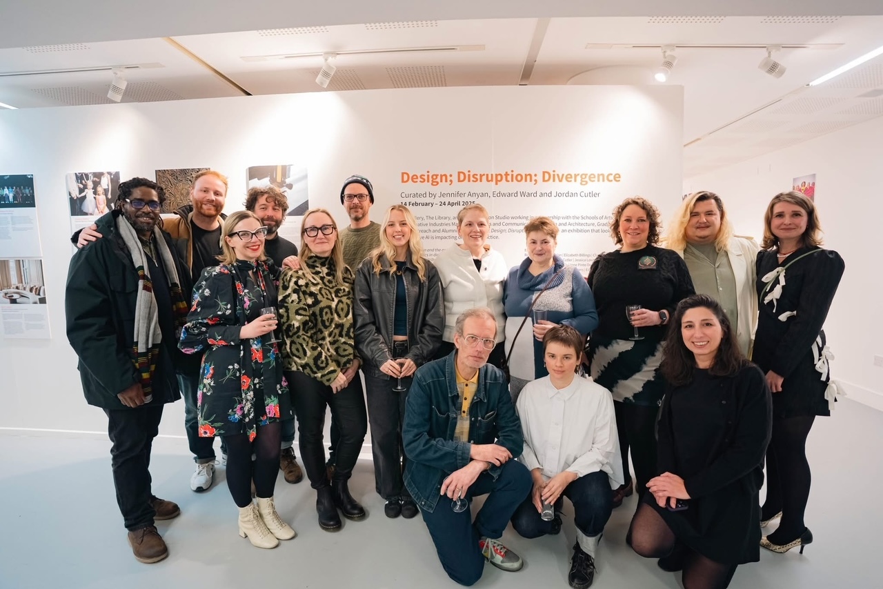 Group of exhibiting artists from the "Design; Disruption; Divergence" exhibition posing for a photo at TheGallery, Arts University Bournemouth.