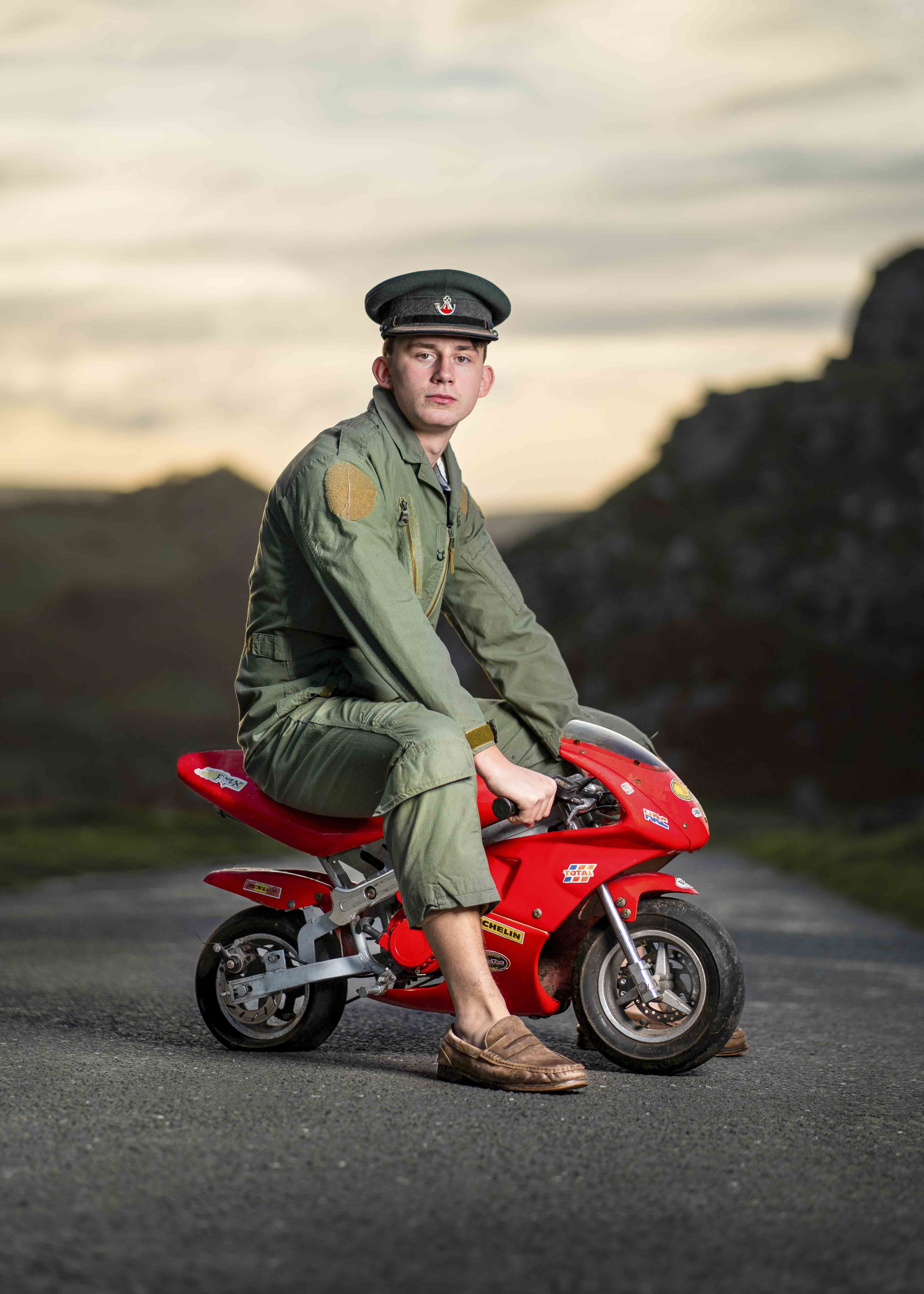 A man in military-style uniform on a mini red motorbike.
