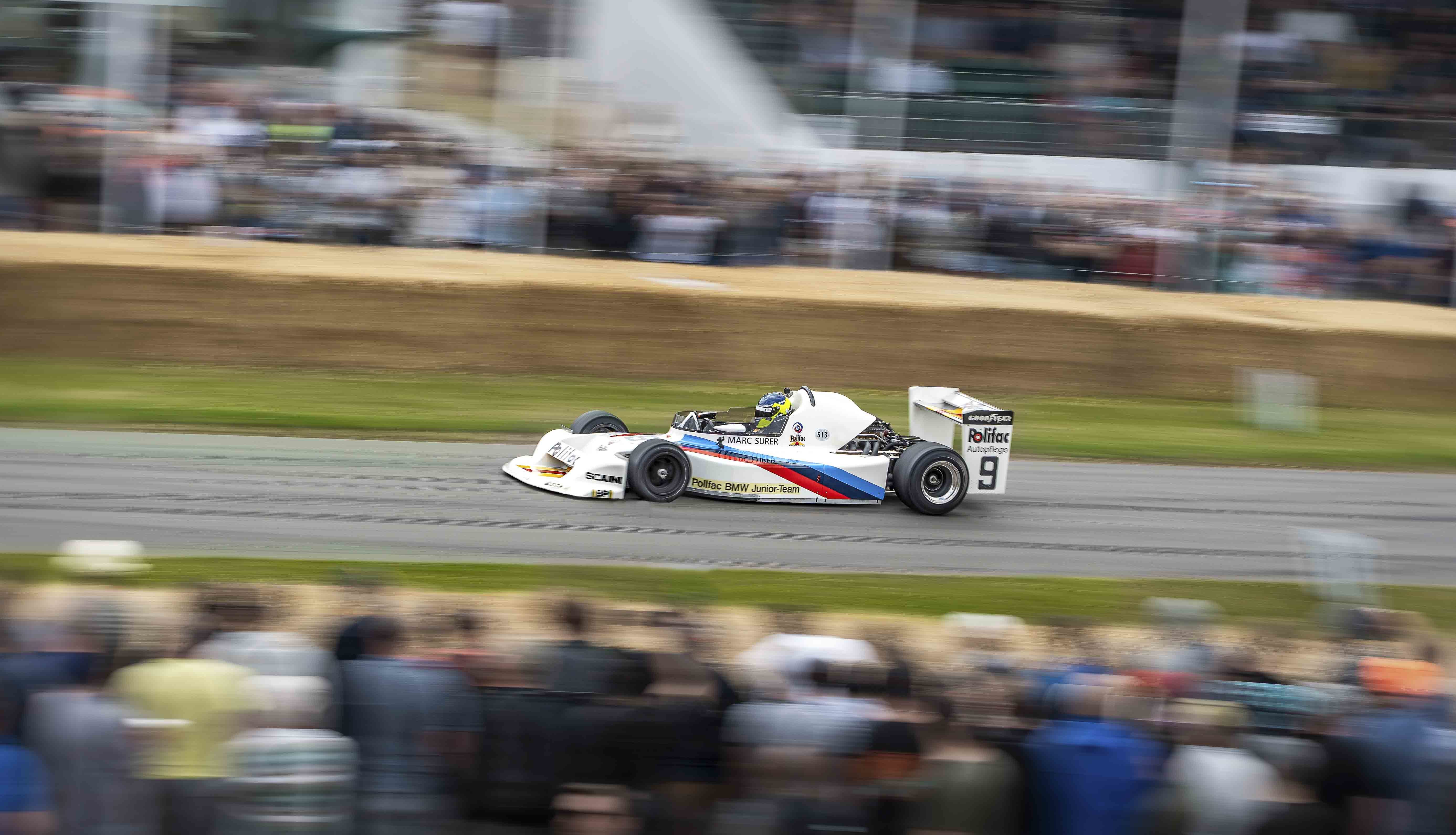 An F1 race car speeding round the track with onlookers.